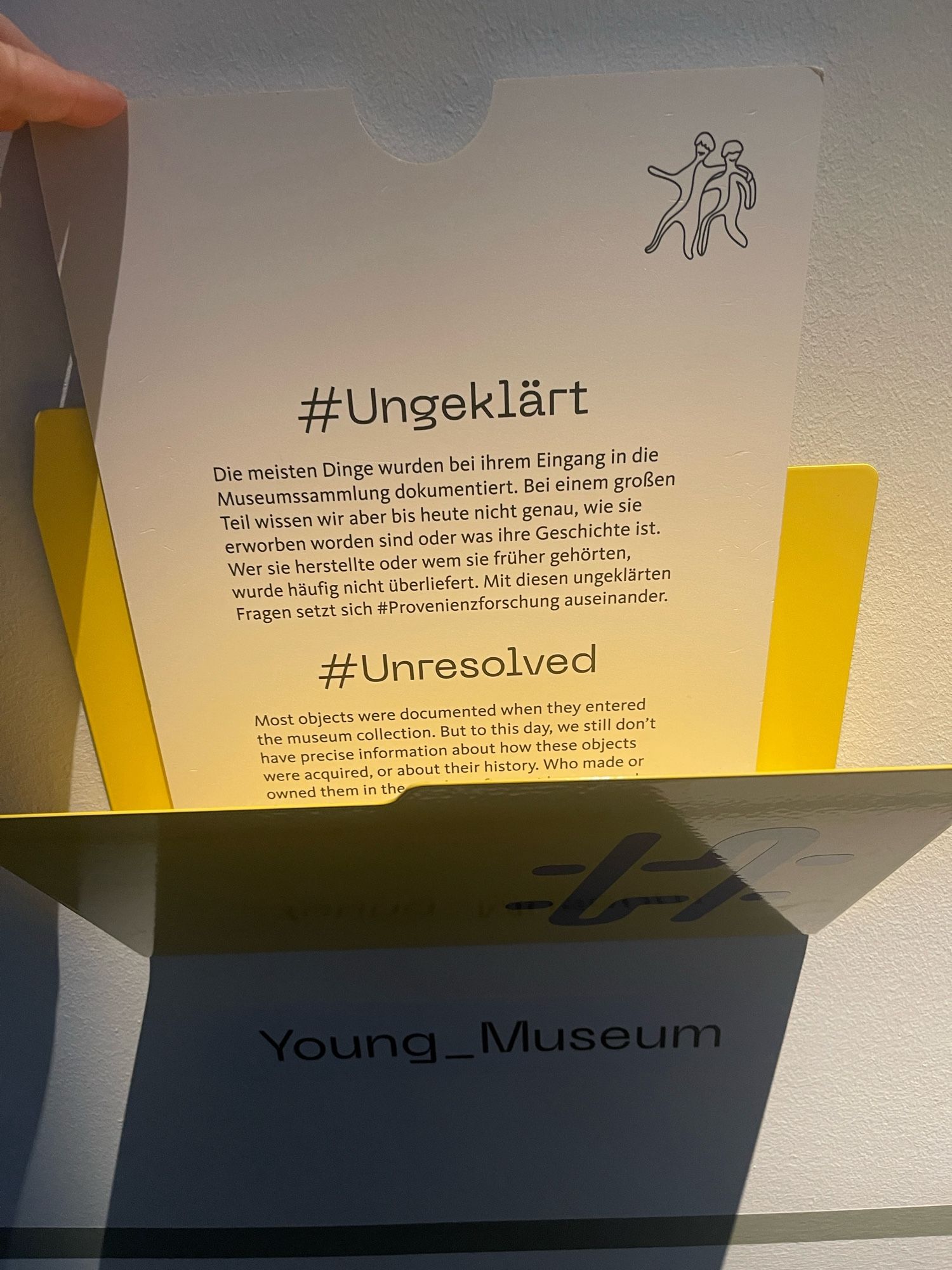 Beschreibungstext in einer gelben Ablage mit Titel „Young Museum“ unter dem # Ungeklärt zum oftmals unbekannten Hintergrund der Beschaffung von Dingen, die jetzt im Museum stehen