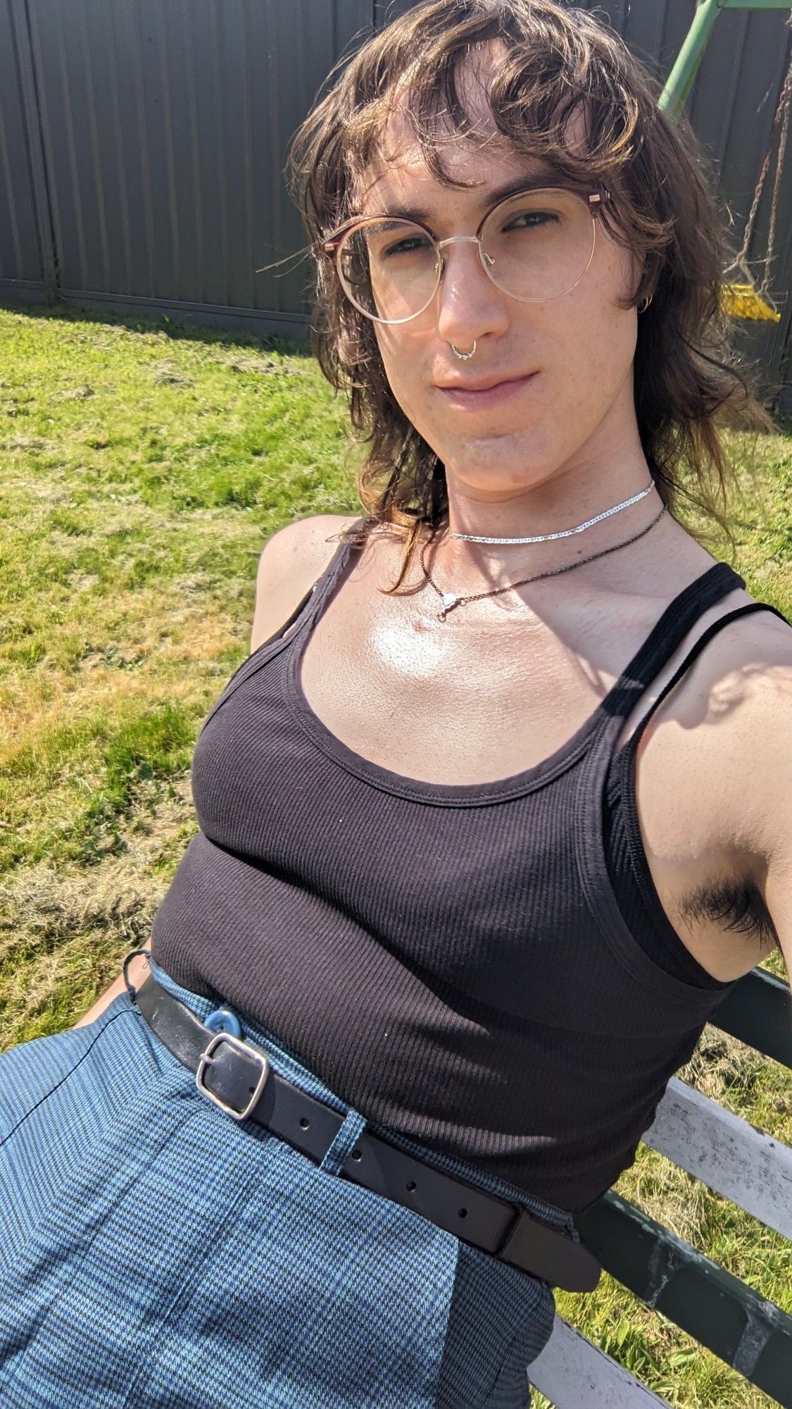 Selfie of a woman in a black singlet sitting outside on a sunny day