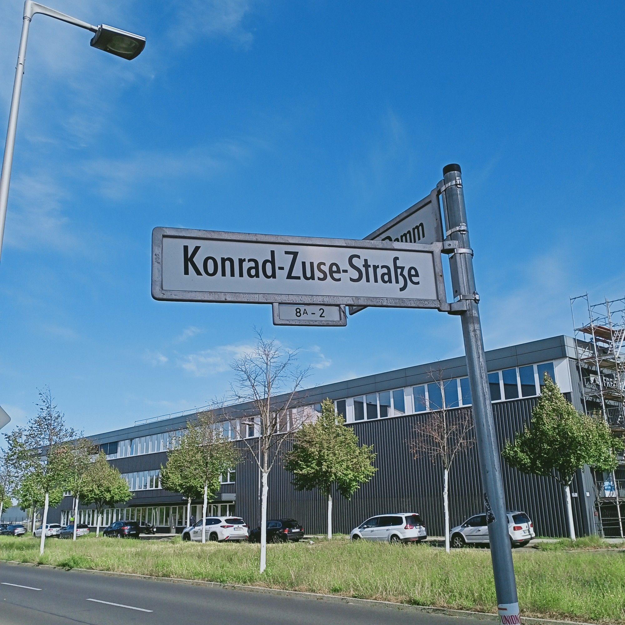 Straßenschild der Konrad-Zuse-Straße mit Industrieflachbau im Hintergrund