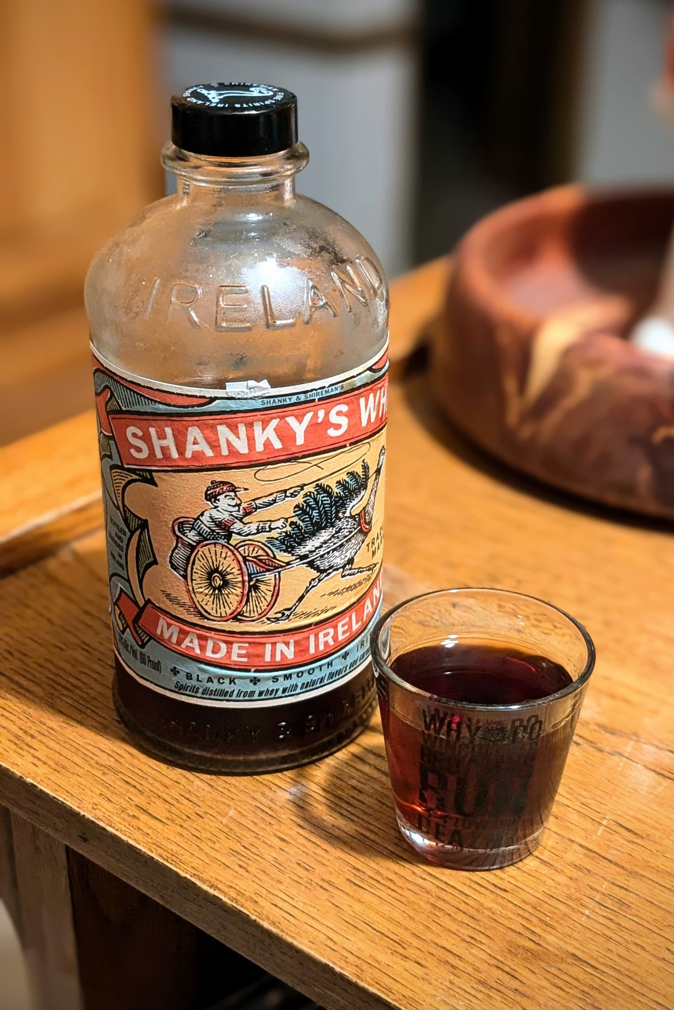 bottle of shanky's whip irish black liqueur next to a triple shot of shanky's in a supernatural shot glass