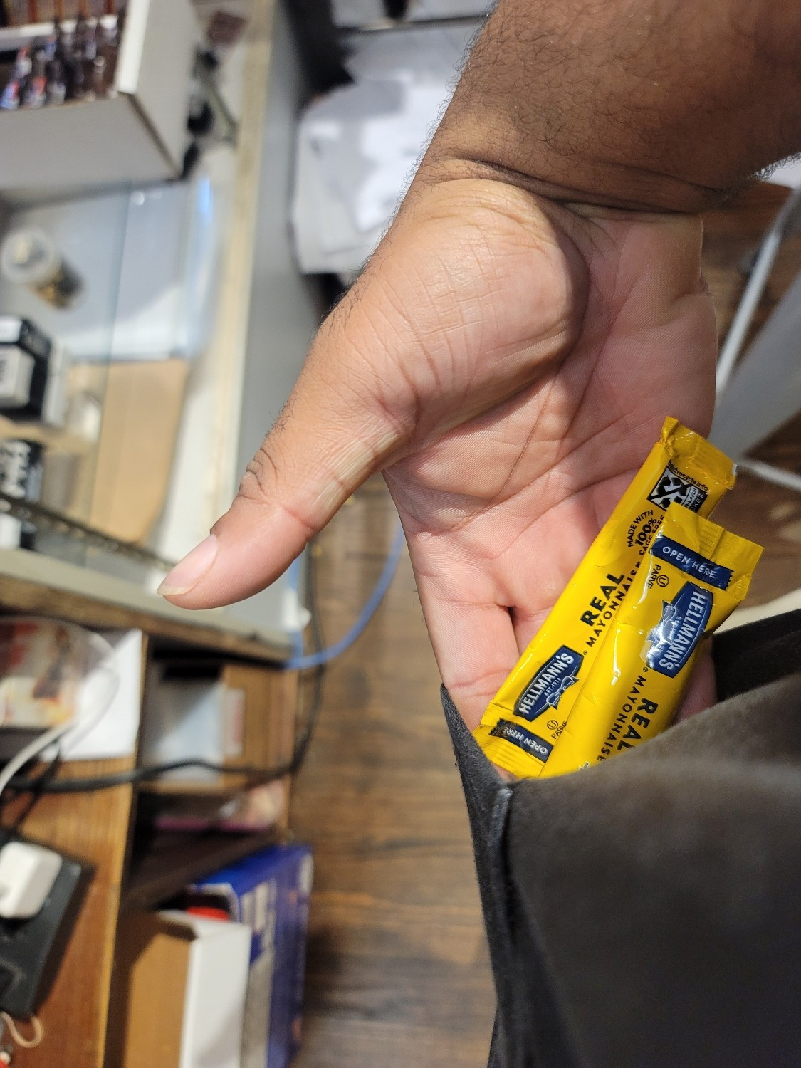 Two packs of single use mayonnaise packets being pulled out of a pocket.