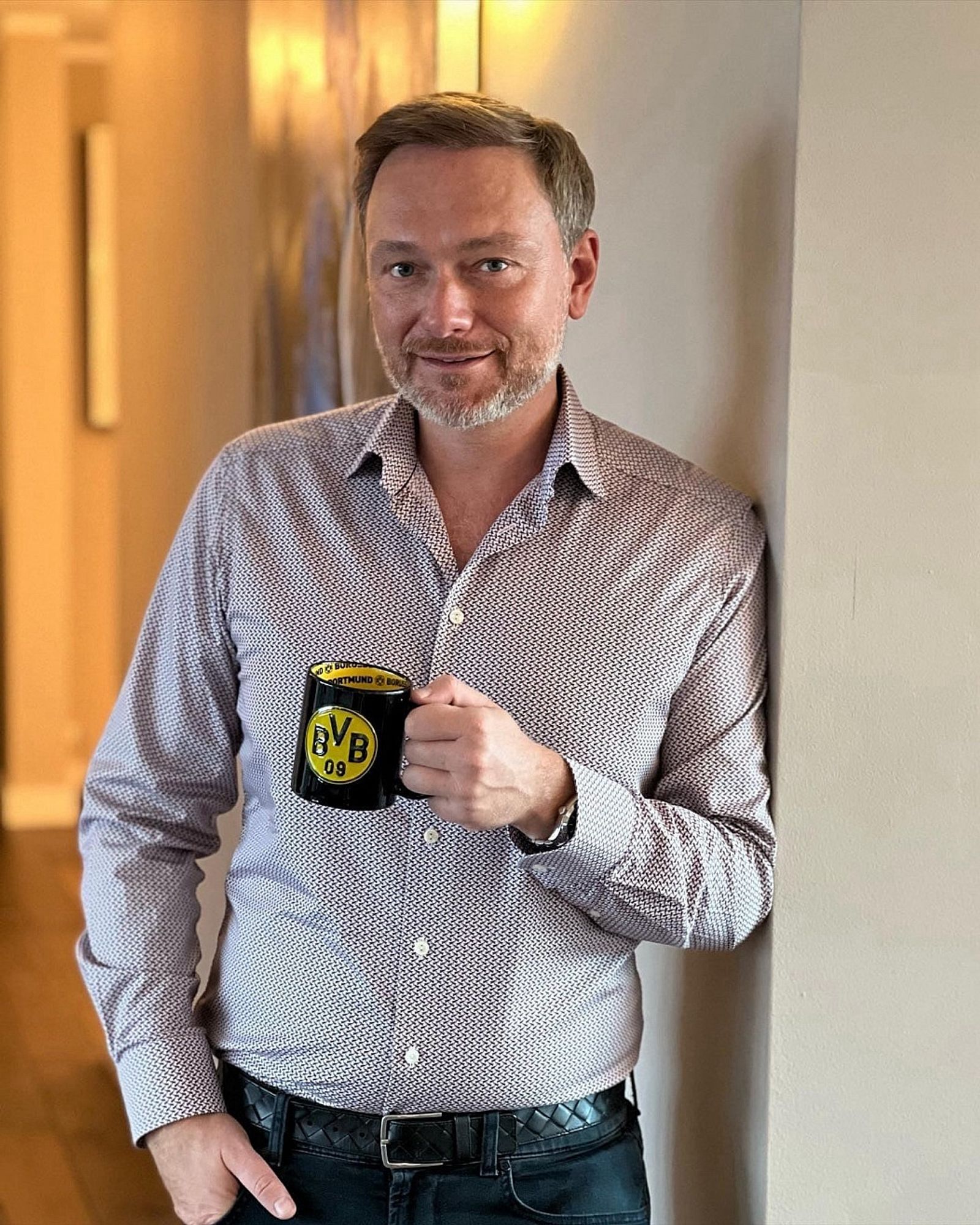 Christian Lindner in Jeans und Hemd mit einer BVB Tasse in der Hand