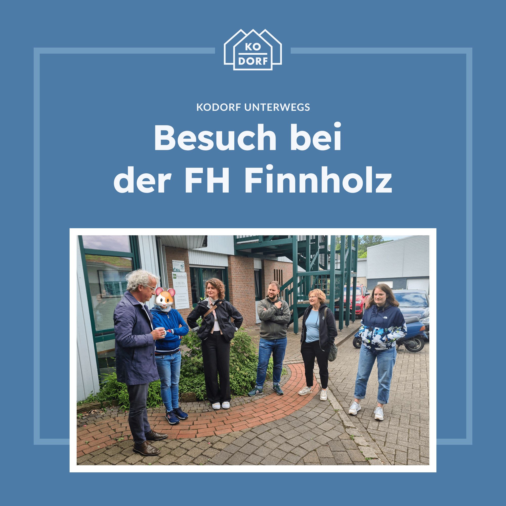 Eine fröhliche Gruppe von Menschen, die die Holzbaufirma FH Finnholz besuchen. Links steht ein Herr in einem blauen Sakko, der redet. Neben ihm ist eine Person mit einer Micky-Maus-Gesichtsmaske zu sehen, die zuhört. Eine Frau in schwarzer Jacke und weißem T-Shirt ist ebenfalls ganz Ohr und scheint begeistert zu sein. Zwei weitere Personen, eine mit einem grünen Kapuzenpulli und eine mit blauer Jacke, stehen ebenfalls in der Gruppe und lächeln. Der Hintergrund zeigt das Gebäude der FH Finnholz mit einer Treppe und mehreren geparkten Autos. Es herrscht eine lockere, angenehme Atmosphäre.