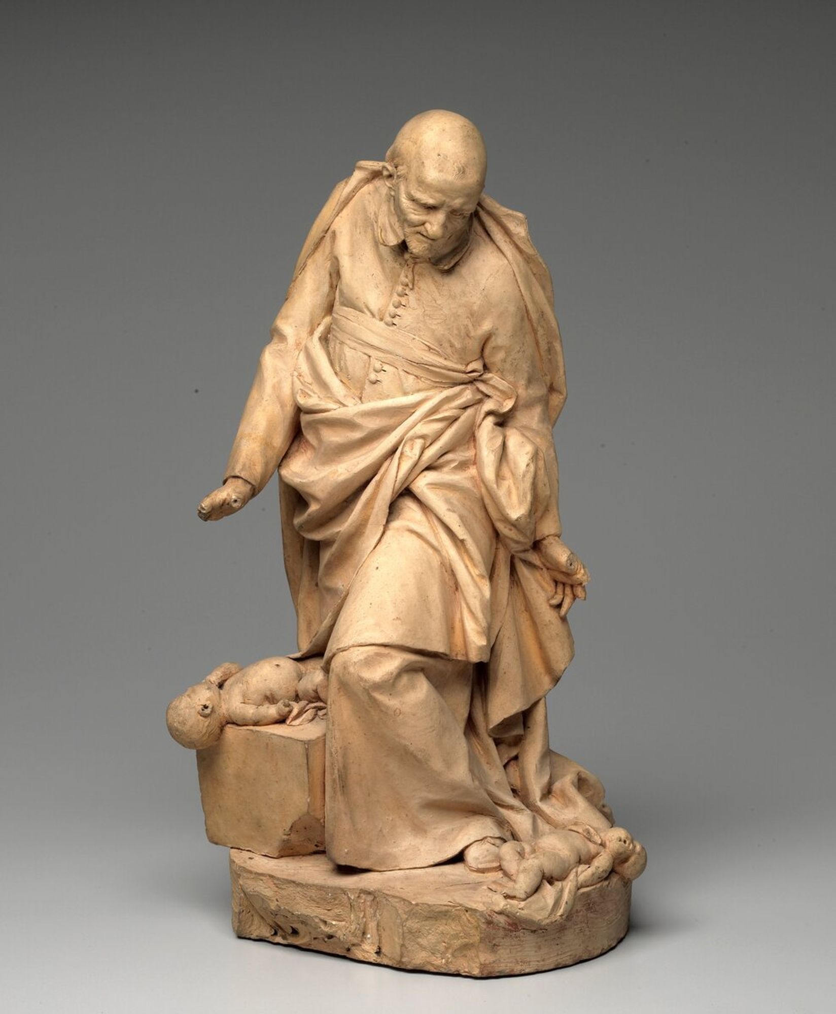 Stouf's representation of the saint shows him standing and looking down at two dead infants at his feet. His facial expression registers his horror at he devastations of the "Fronde"--the civil war of 1648-1653. The resultant life-size statue was the sculptor's first major work.
Saint Vincent de Paul (1581–1660) dedicated his life to helping the poorest of the poor in France, including abandoned and abused children. About a hundred years later, during the Enlightenment, when the French celebrated scientific reasoning and individual liberty, he was one of the few religious personages honored with a statue in the Great Men of France series, installed in the Louvre’s Grande Galerie. This terra-cotta model is the only record of Stouf’s first proposal for the statue. Severely criticized for showing only the saint’s compassion and not his active deed of charity, Stouf modified the sculpture. His final version shows the saint lifting a child off the ground, symbolizing the children’s salvation.