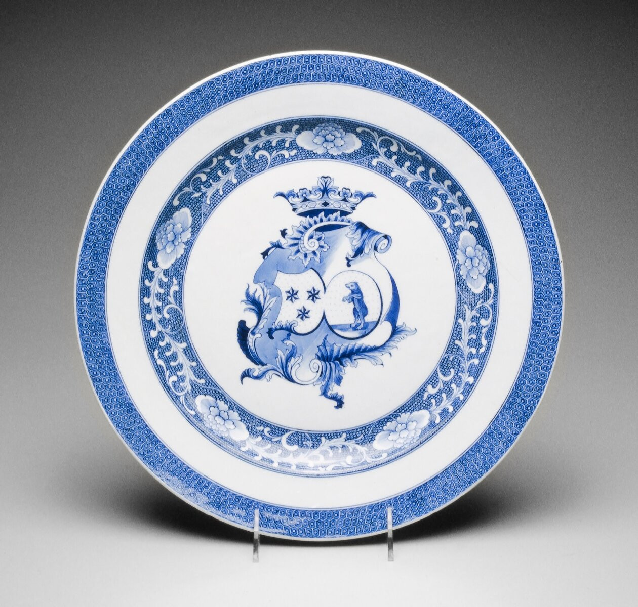 blue and white; large coat of arms of Peers of Baraud and Maraschel of Forez; scrolls and border with cell pattern bands
White bodied porcelain with underglaze blue decoration was the earliest type imported to the West, setting off the original craze for collecting porcelain in Europe. It has never truly gone out of favor, even today. This 18th century plate bears the combined coats of arms of the Peers of Baraud and Maraschal of Forez families of France.