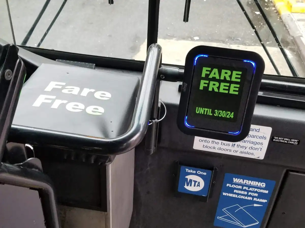 Close up of front of bus interior showing digital screen where cards are tapped to collect bus far. Screen says "FARE FREE UNTIL 3/30/2024." On the right is a farebox covered with a sign that also says "FARE FREE."