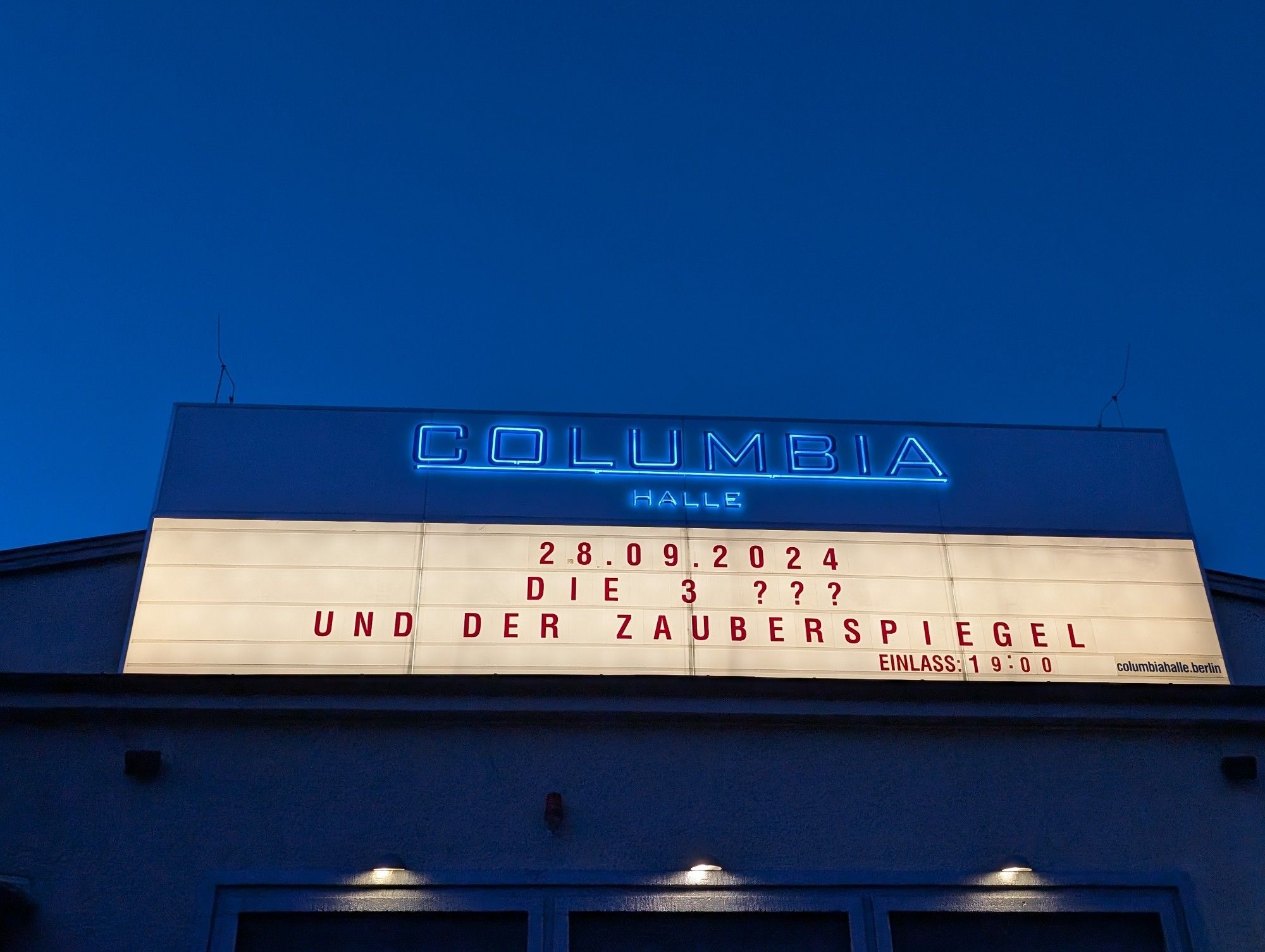 Auf diesem Bild ist das Schild der columbiahalle Berlin zu sehen. In der ersten Reihe steht das Datum 28. September 2024 in der Reihe. Darunter steht die Drei ???
Und in der letzten Reihe steht: und der zauberspiegel