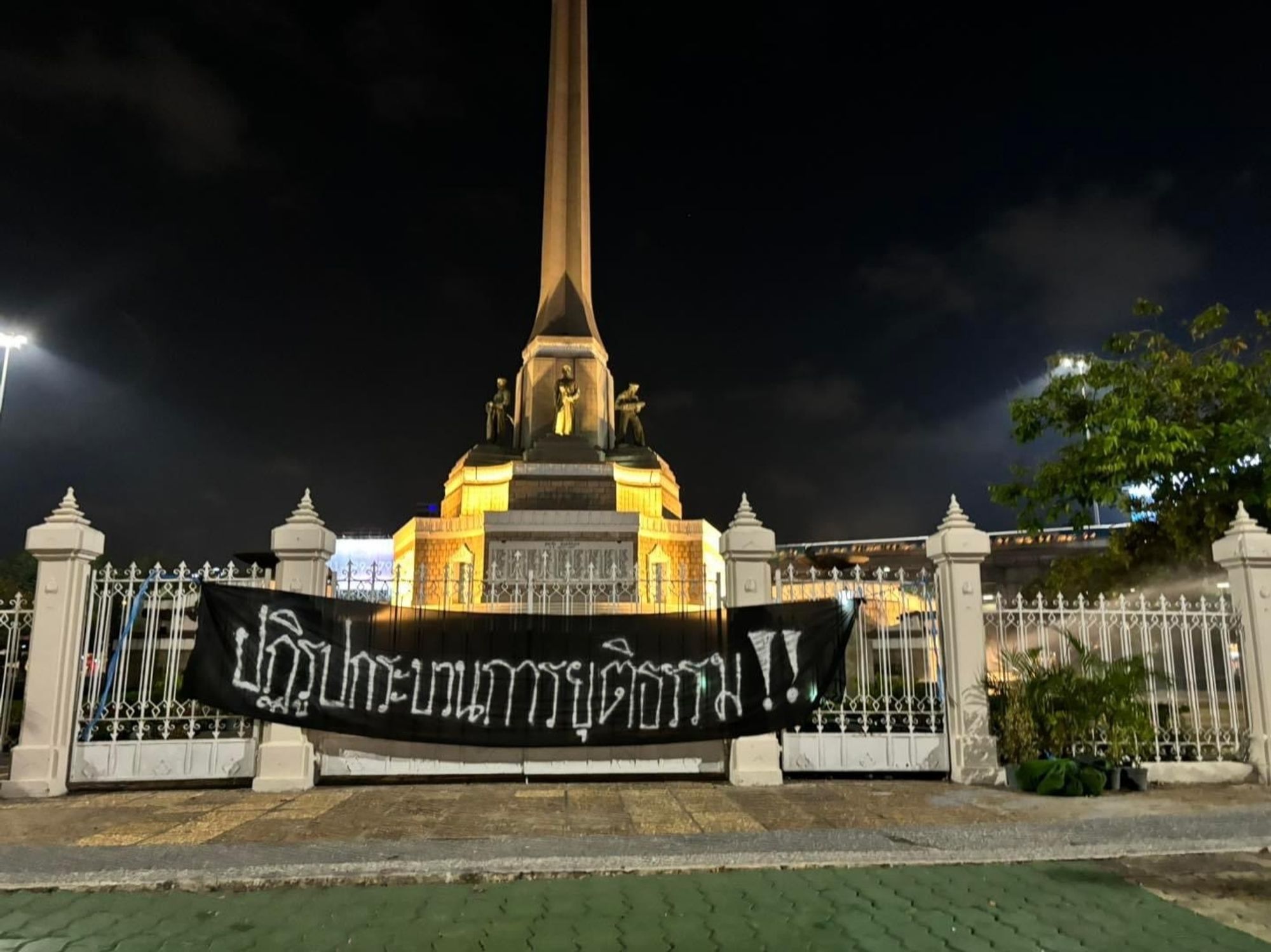 Banner attached to some railings by a monument in Bangkok. Reads (in thai) Reform the justice system.