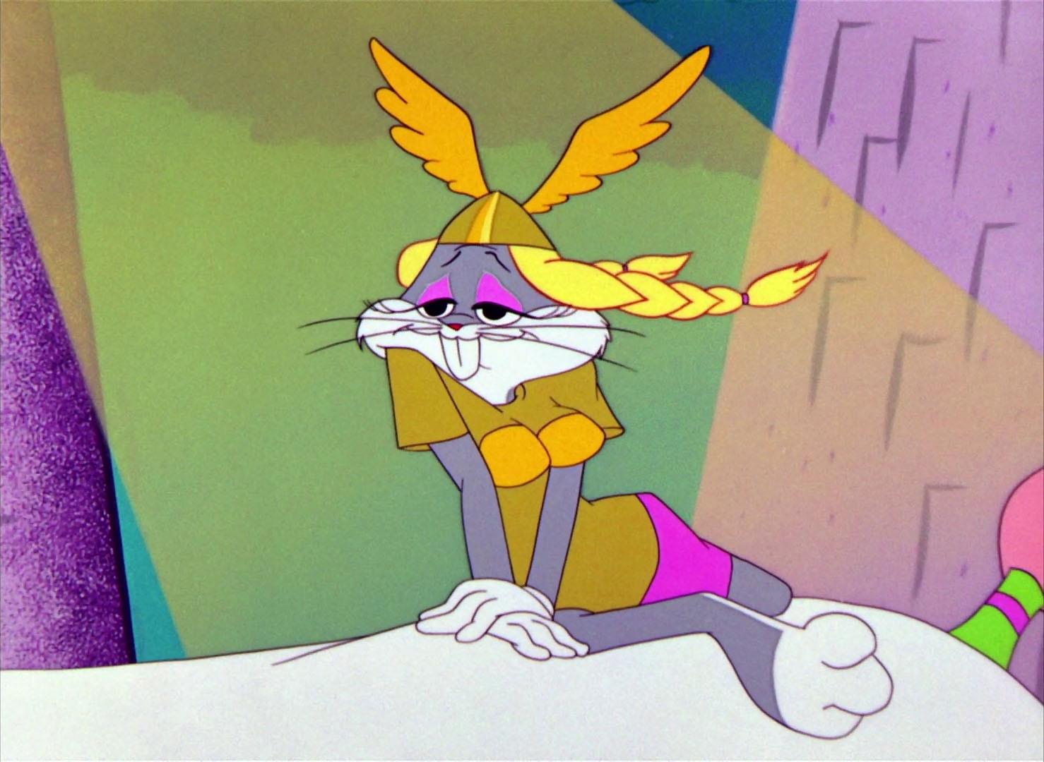 Bugs Bunny sultrily leans on their hands with a leg half stretched with lightly curled toes. They ride bareback and somewhat sidesaddle on a large white horse. Bugs wears a golden winged helmet to match a mustard tunic top. From under the helmet, two blonde braids flow behind. Squeezed between their arms are two bright-gold prominences over their tunic. Bugs' side swooped eyelashes and lowered eyelids expose pink eyeshadow to match a pink skirt.