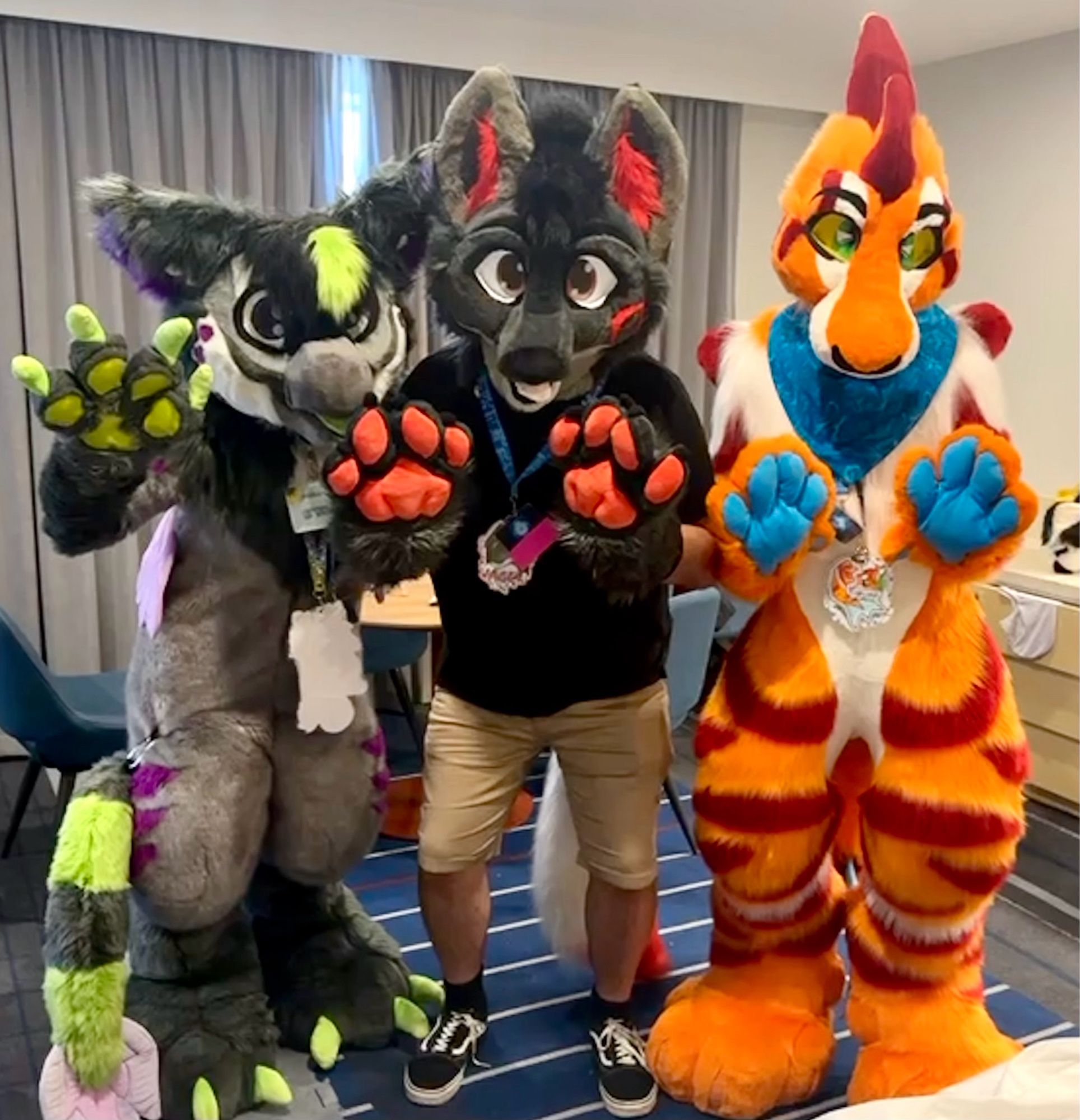 Three fursuiters standing together posing for a photo