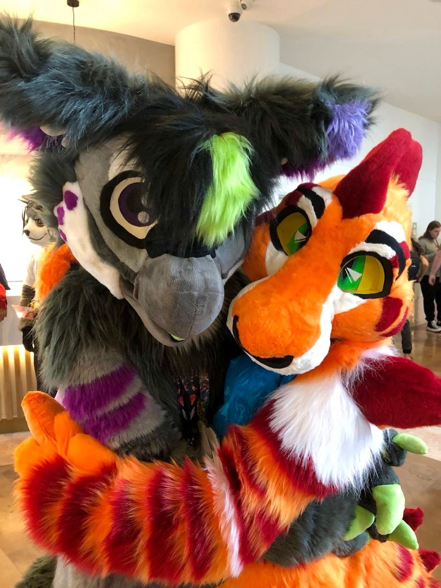 A gryphon fullsuiter hugging a Shark hound Fullsuiter while looking towards the camera for a photo