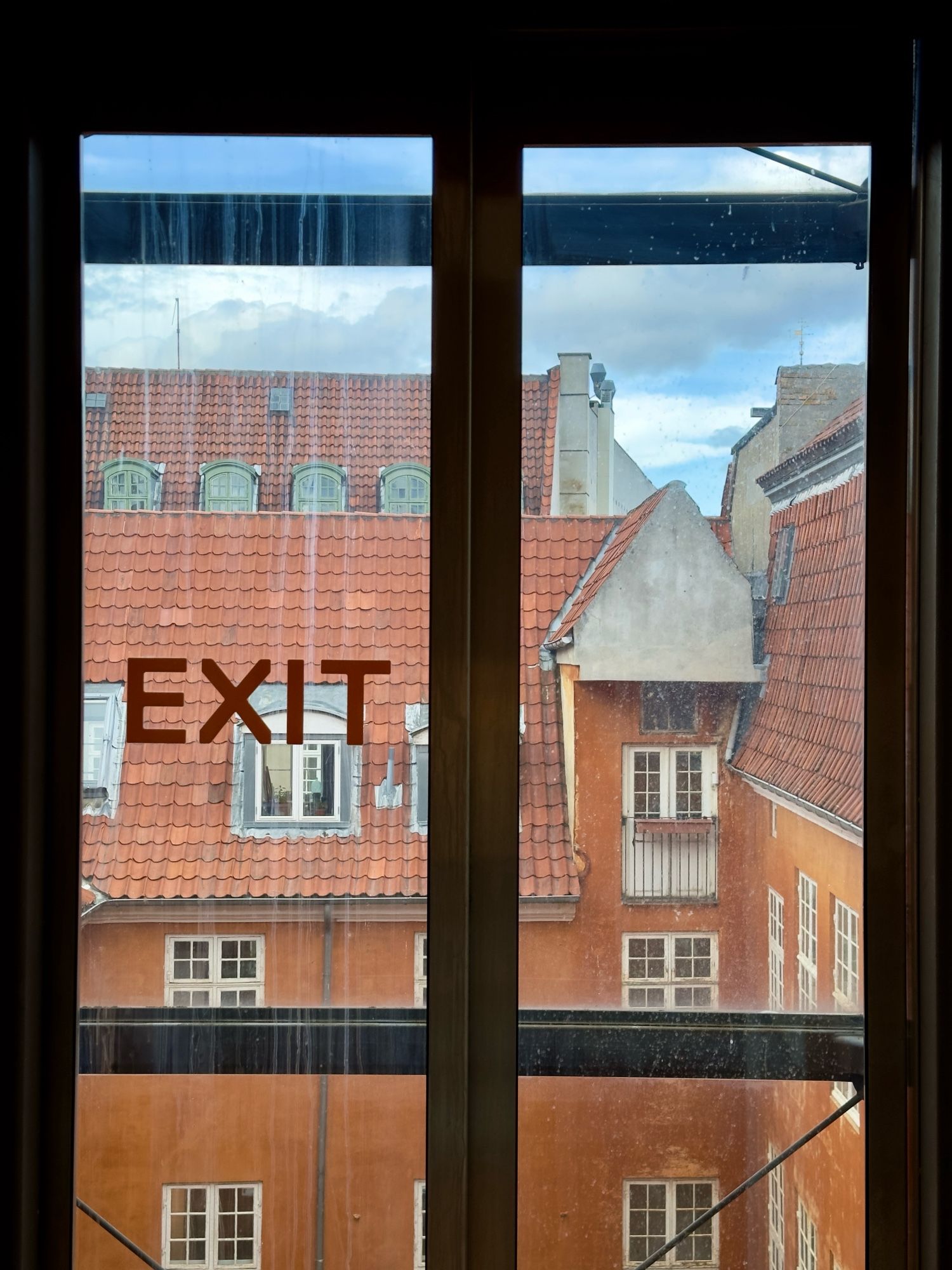 Exit-teksti ikkunassa, taustalla vanha talo.