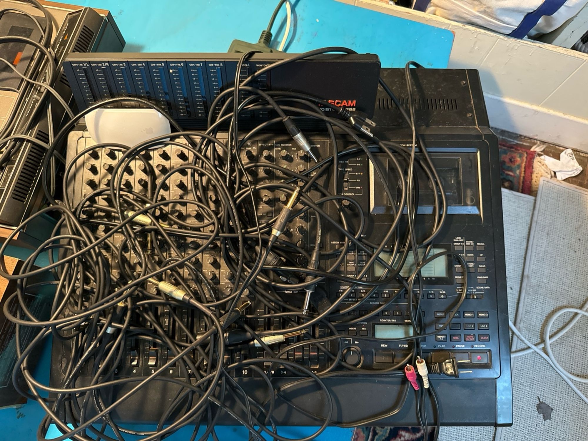 a tascam 688 console multitrack cassette recorder that stopped working a few days ago, now under a pile of cables waiting for repair