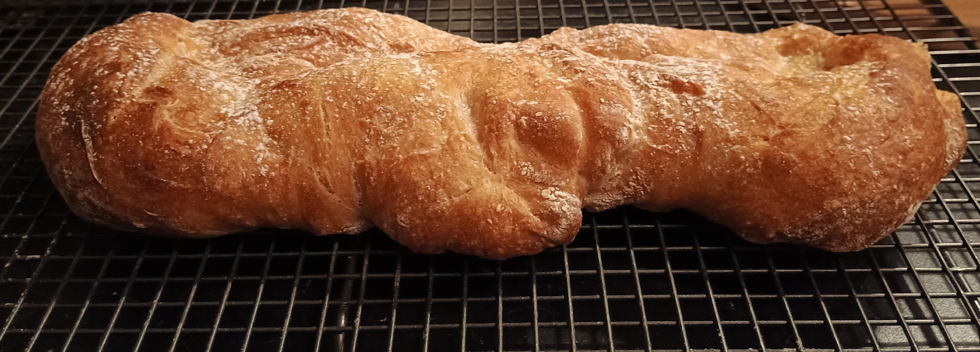 Deeply golden brown ciabatta, from the side. Slightly uneven shape.