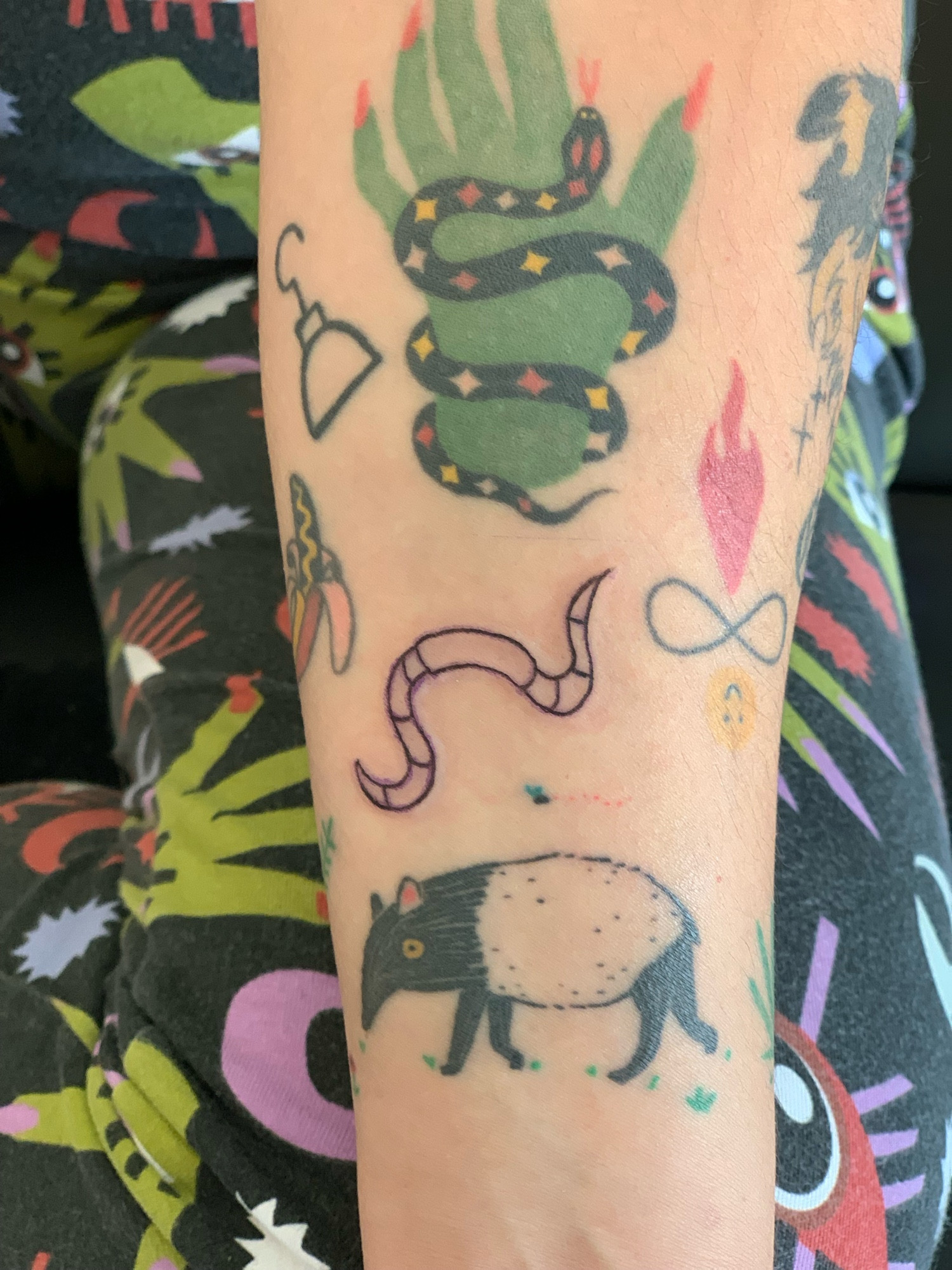 Forearm covered in cool tattoos one is a worm