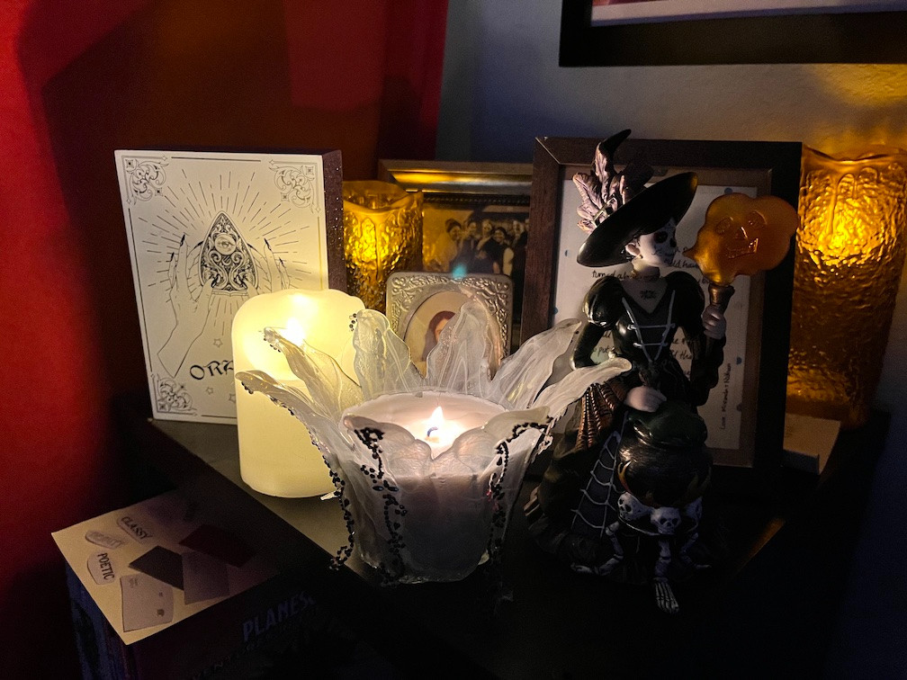 Candles, photographs, and statuettes gathered together in the corner of a dark room.