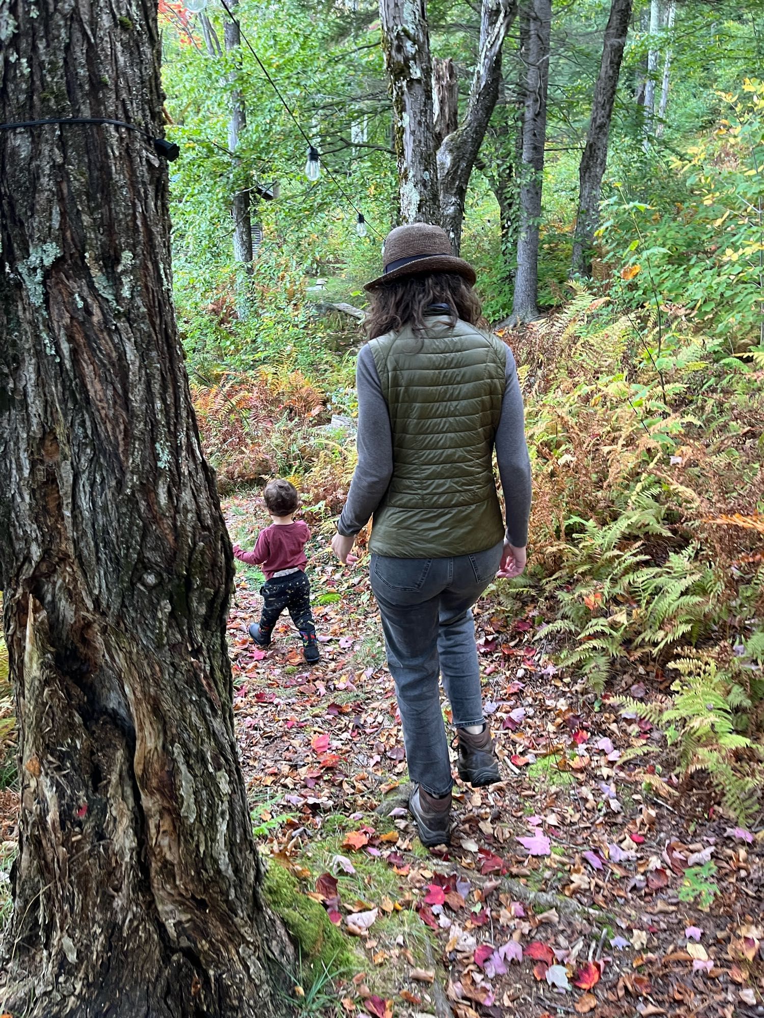 Toddler and mother walking through a wooded path