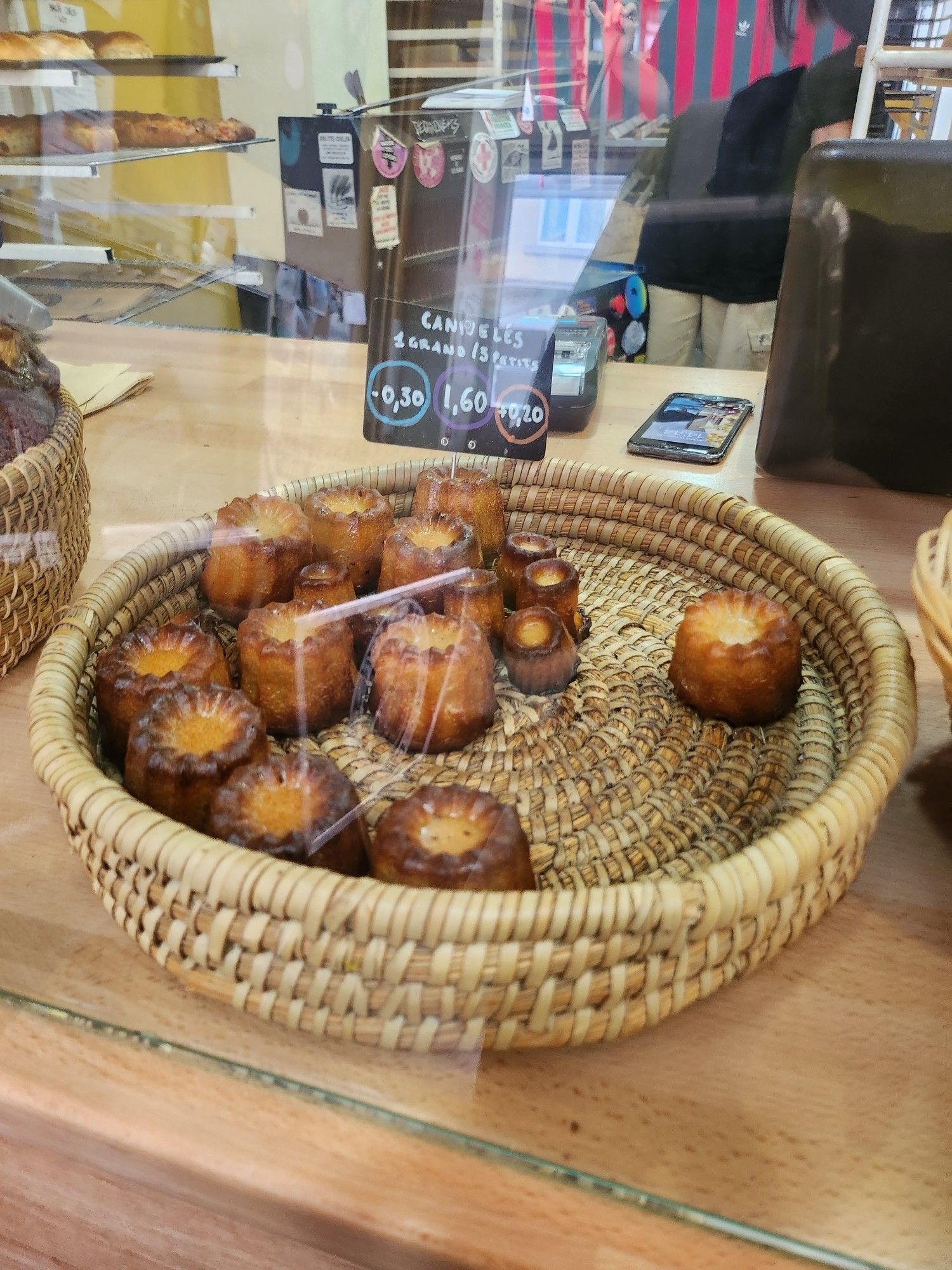 A basket of canelé cakes on a counter