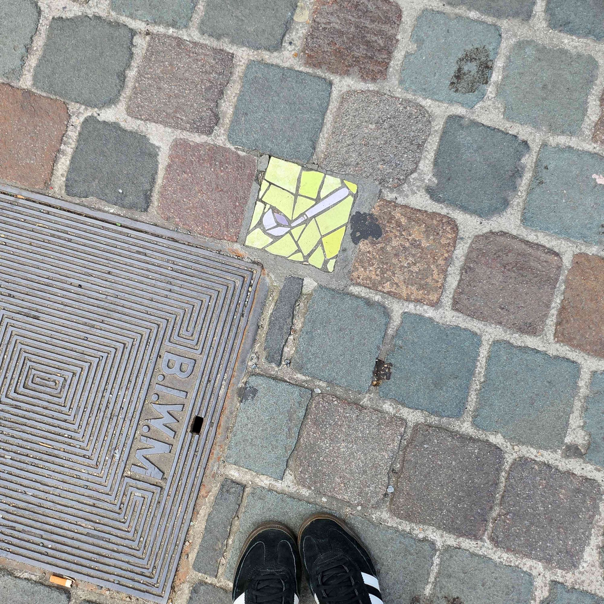 Cobblestone path with a mosaic tile with a ladle on it set into it