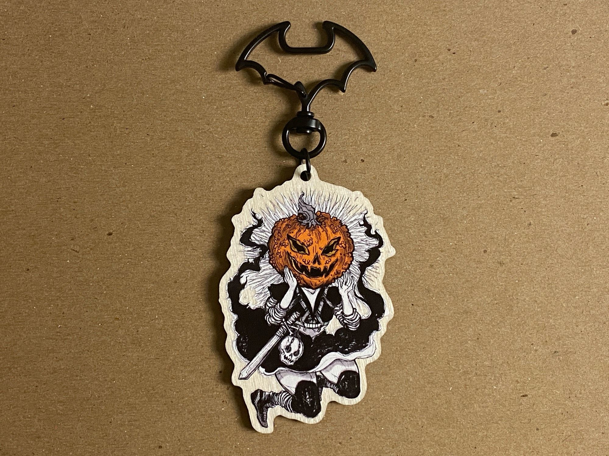 Vintage style Halloween illustration on a synthetic wooden keychain. Art is a black and white image of a human with an orange jack o lantern pumpkin head.