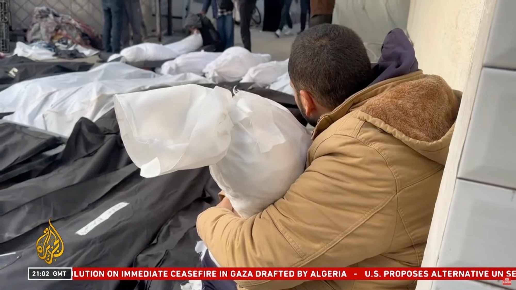 A Palestinian man Abdurrahman holding his daughter’s body wrapped in a white sheet with writing on it and a blood stain.