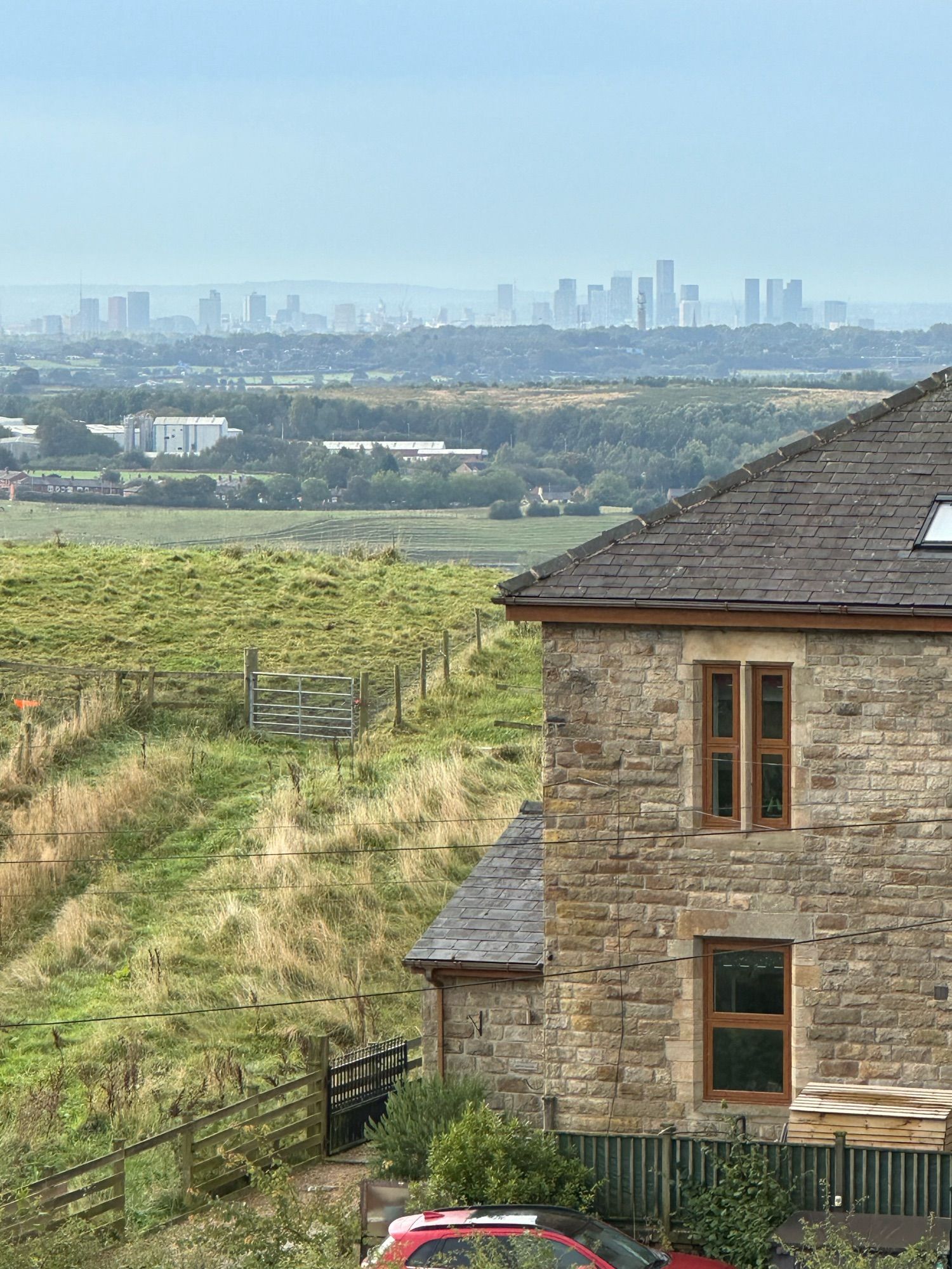 Image of house and fields near St John Bircle with the skyscrapers of Manchester in the distance