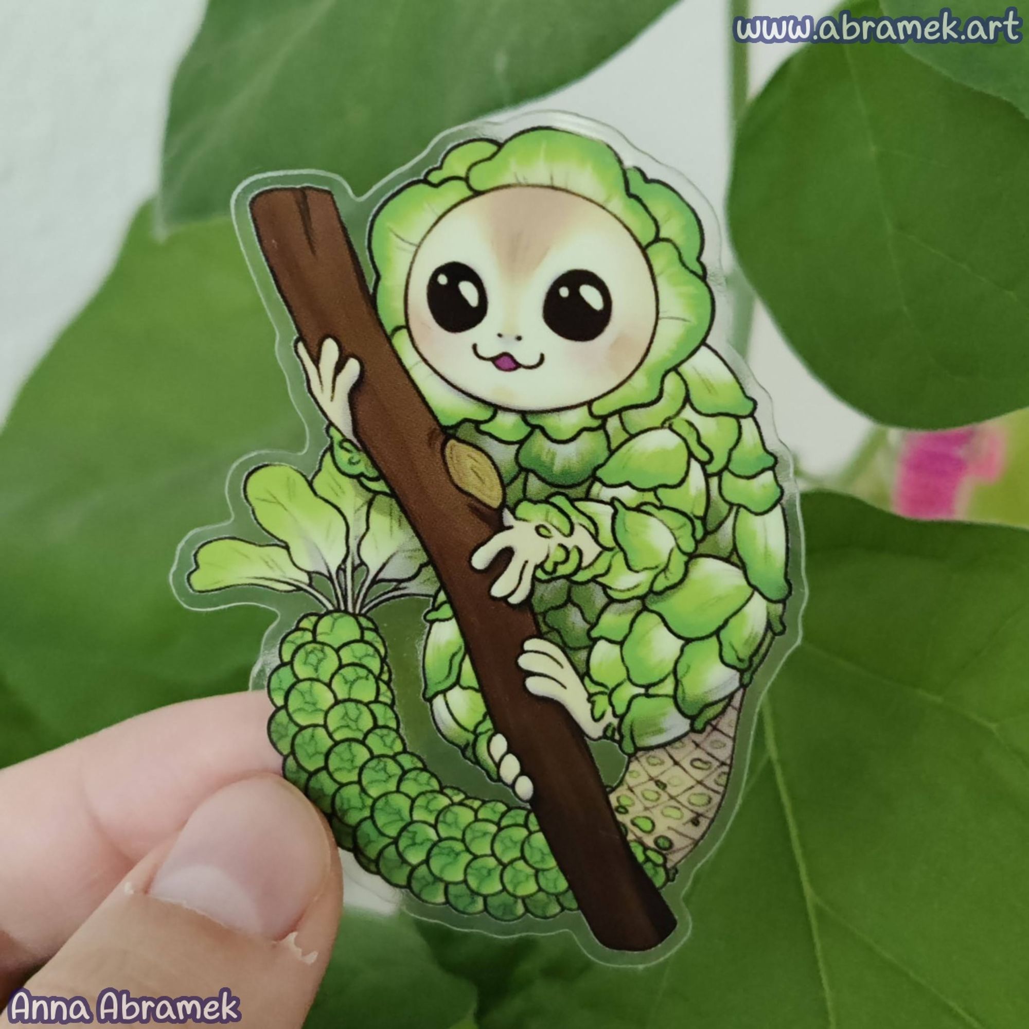 A sticker featuring a cabbage monkey creature sitting on a branch.