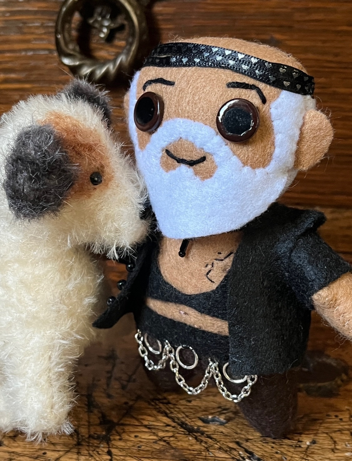 Small felt plush doll of Fang from Our Flag Means Death with a plush dog that looks like a Jack Russell - white with a brown eye patch and black ears.