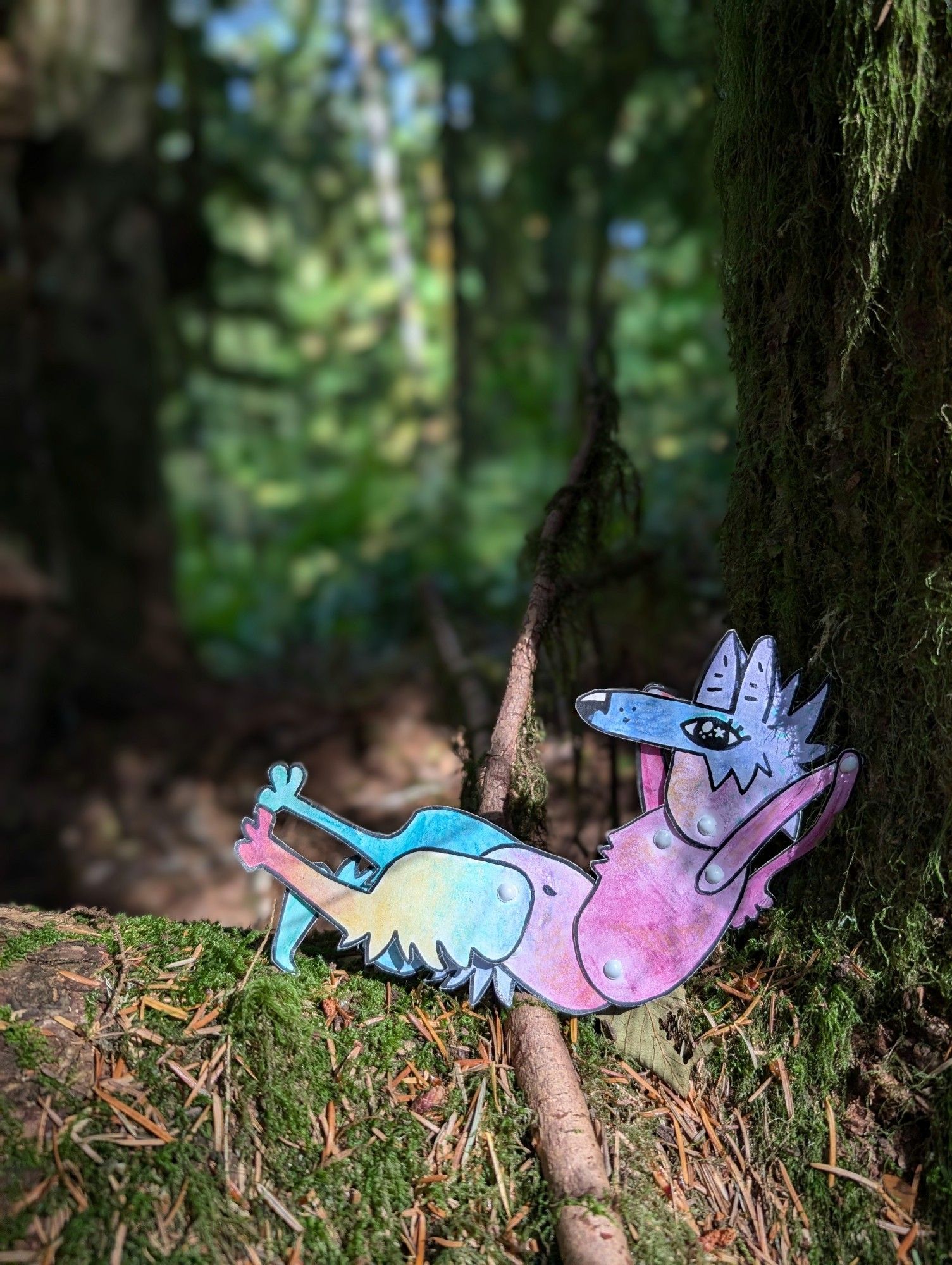 A colorful paper coyote character lounging on a mossy tree nook