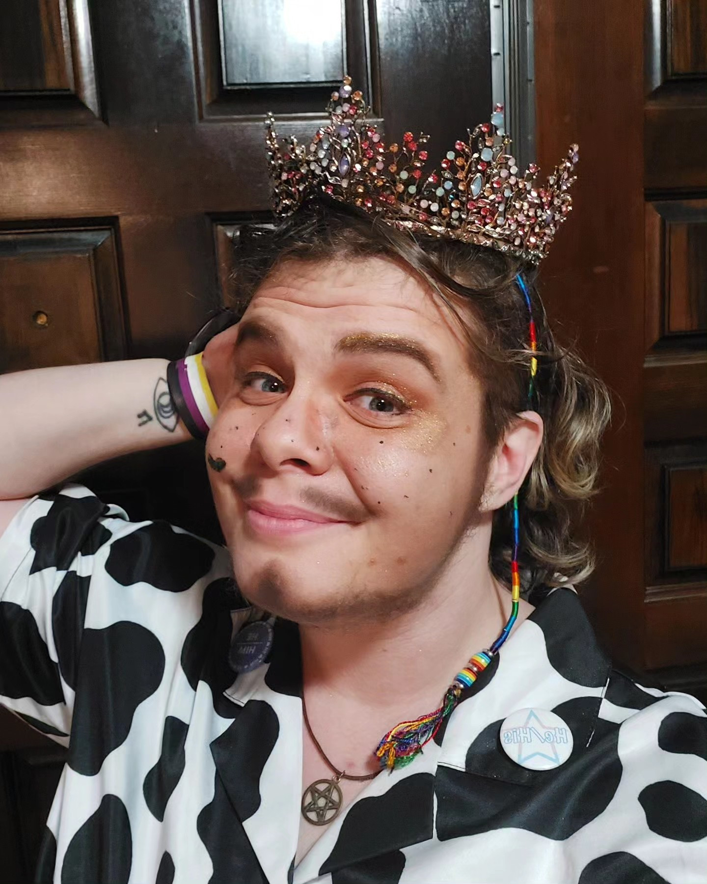 A photo of y'allternative drag king Richard Rider wearing his pageant crown and a cow print shirt.