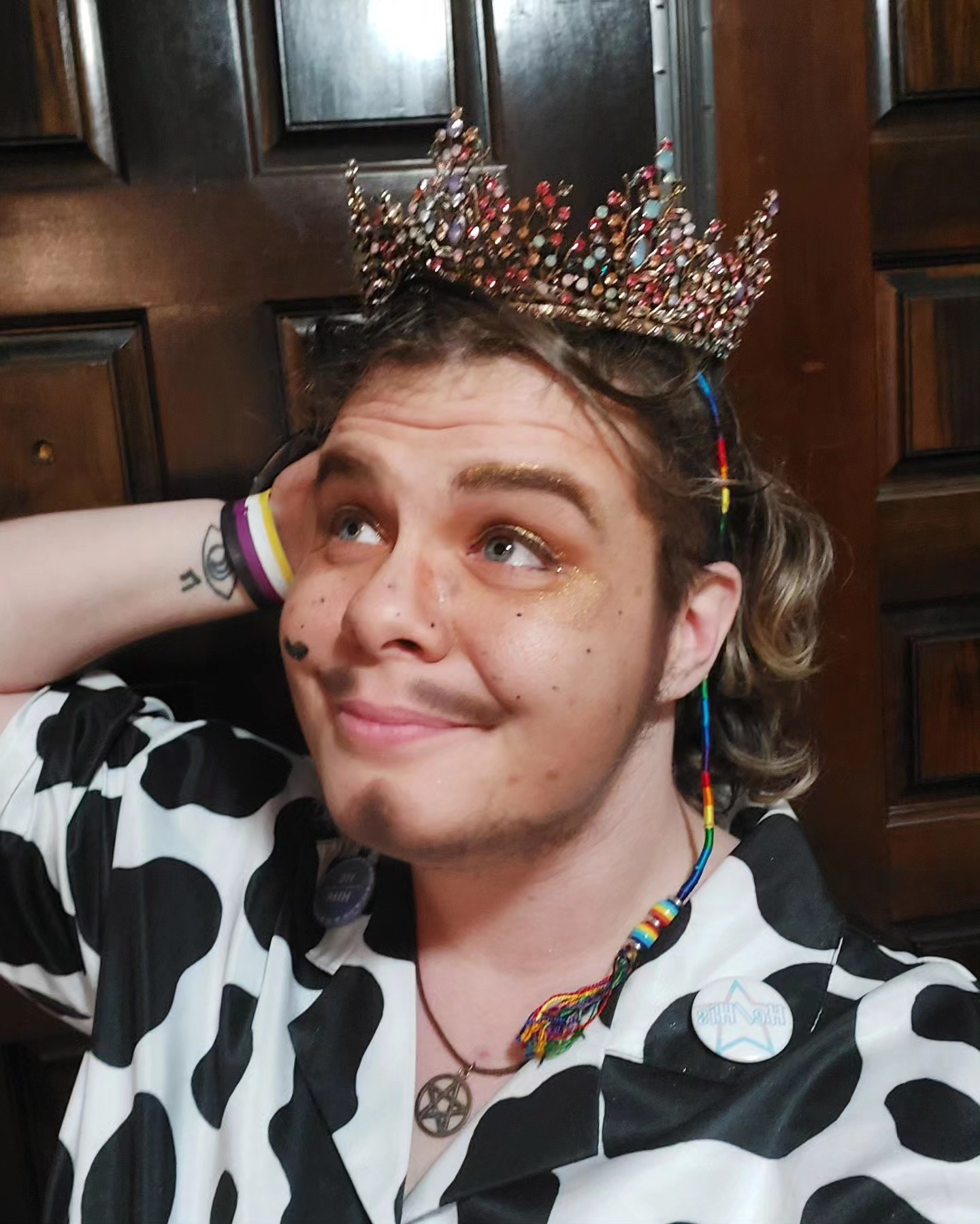 A photo of y'allternative drag king Richard Rider wearing his pageant crown and a cow print shirt.