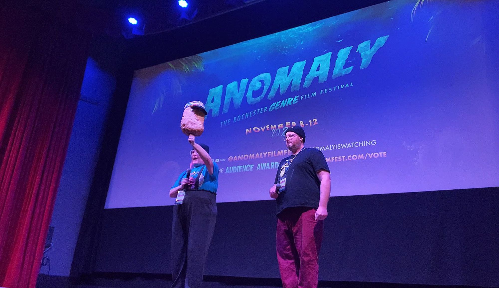 Me holding up the Many-Eyed Potato on stage in front of the screen, Brother Todd behind me for moral support.