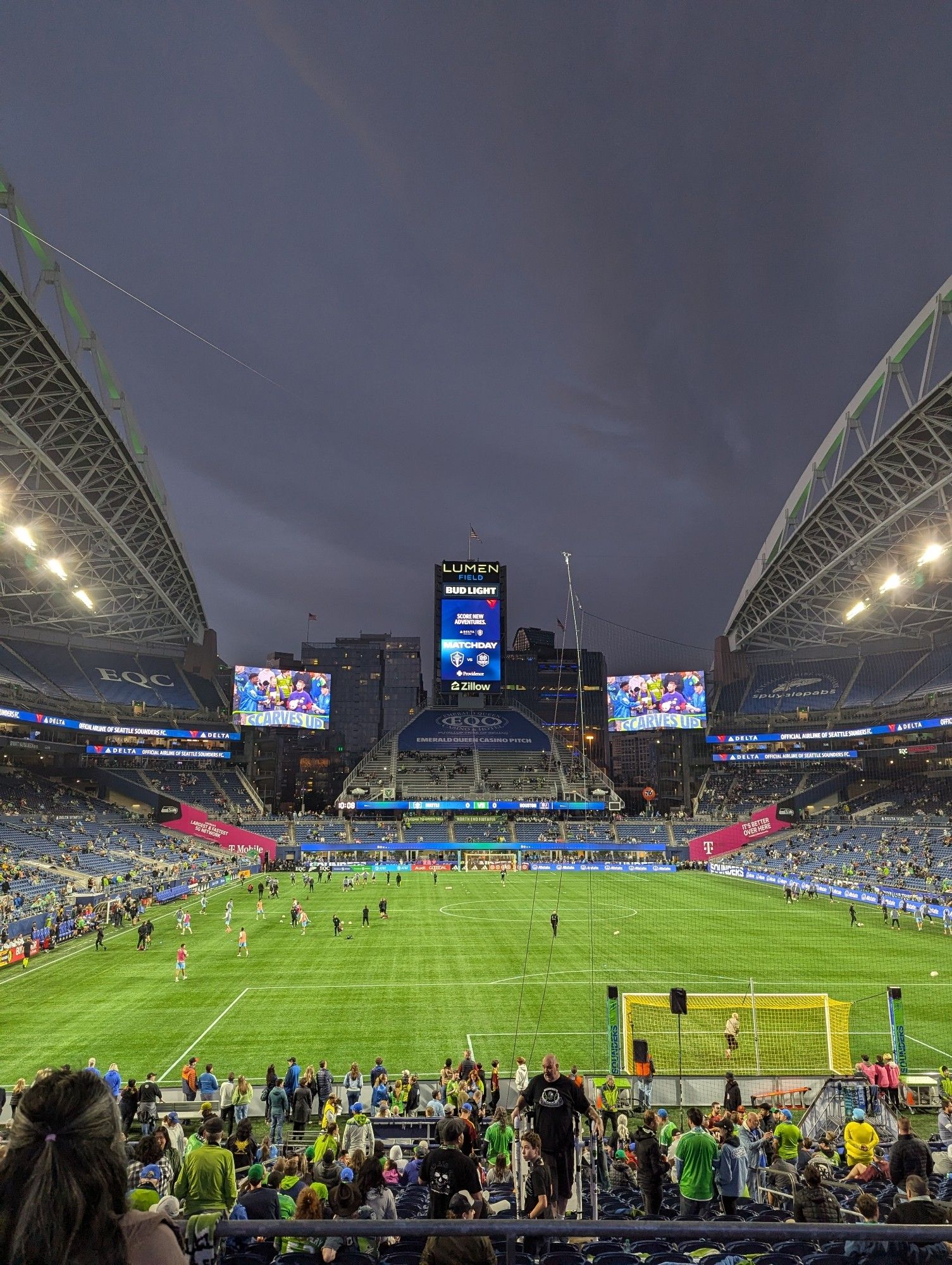 A view of Lumen Field at the start of a Seattle Sounders soccer match, with the green pitch in the foreground and lovely great skies above.