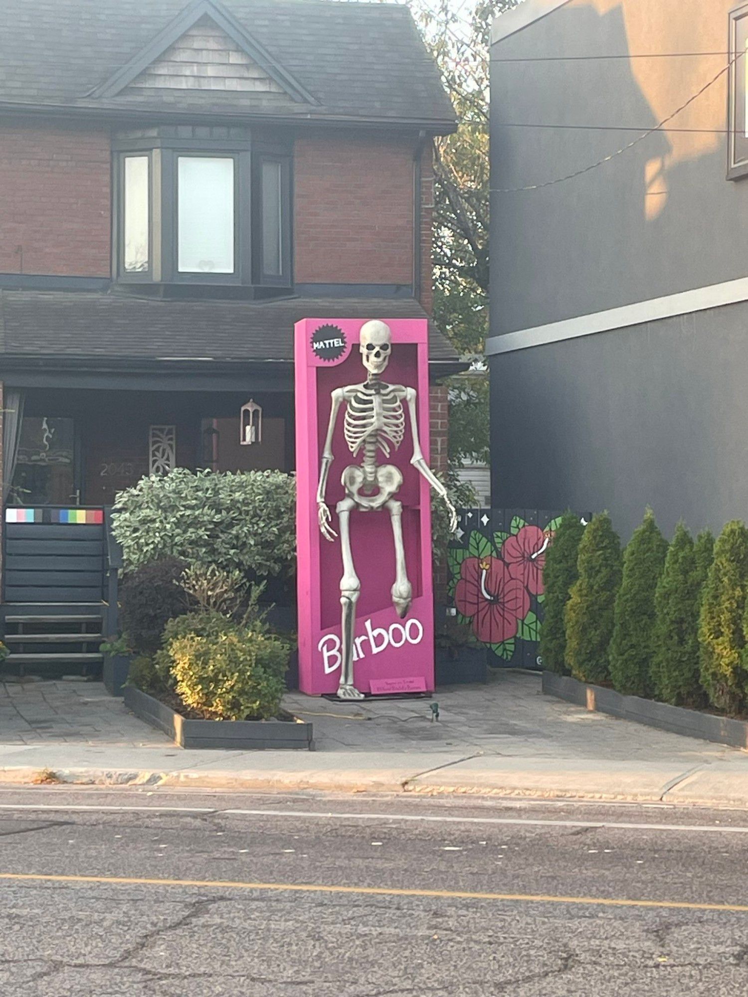 Giant skeleton coming out of a pink Barbie box.