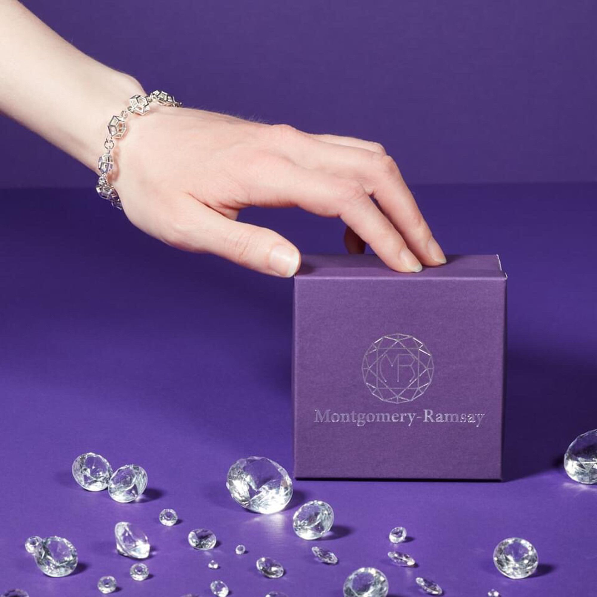 A model wearing a silver bracelet with a branded box an faux diamonds