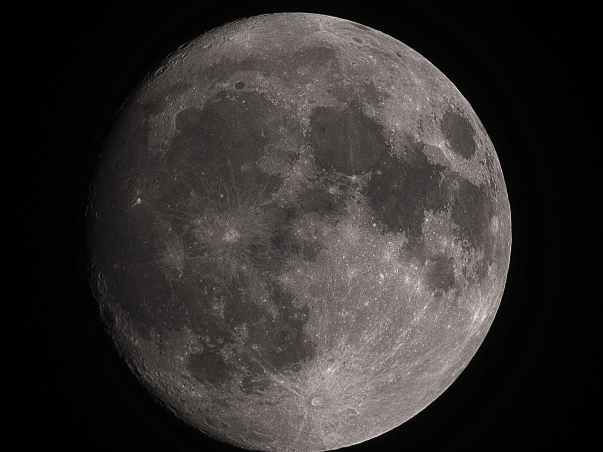 Telescopic image of a nearly full Moon showing smooth, dark lunar plains and bright impact craters.