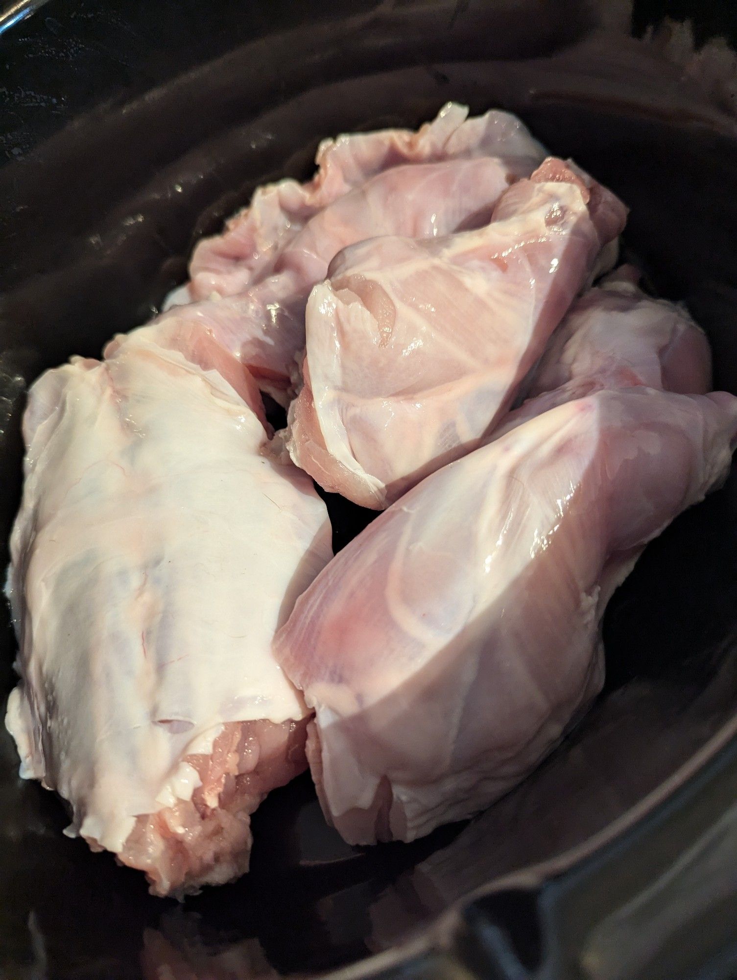 Raw rabbit pieces in a crock pot, 2 forelegs, 2 hind legs, 1 belly flap, 1 back piece