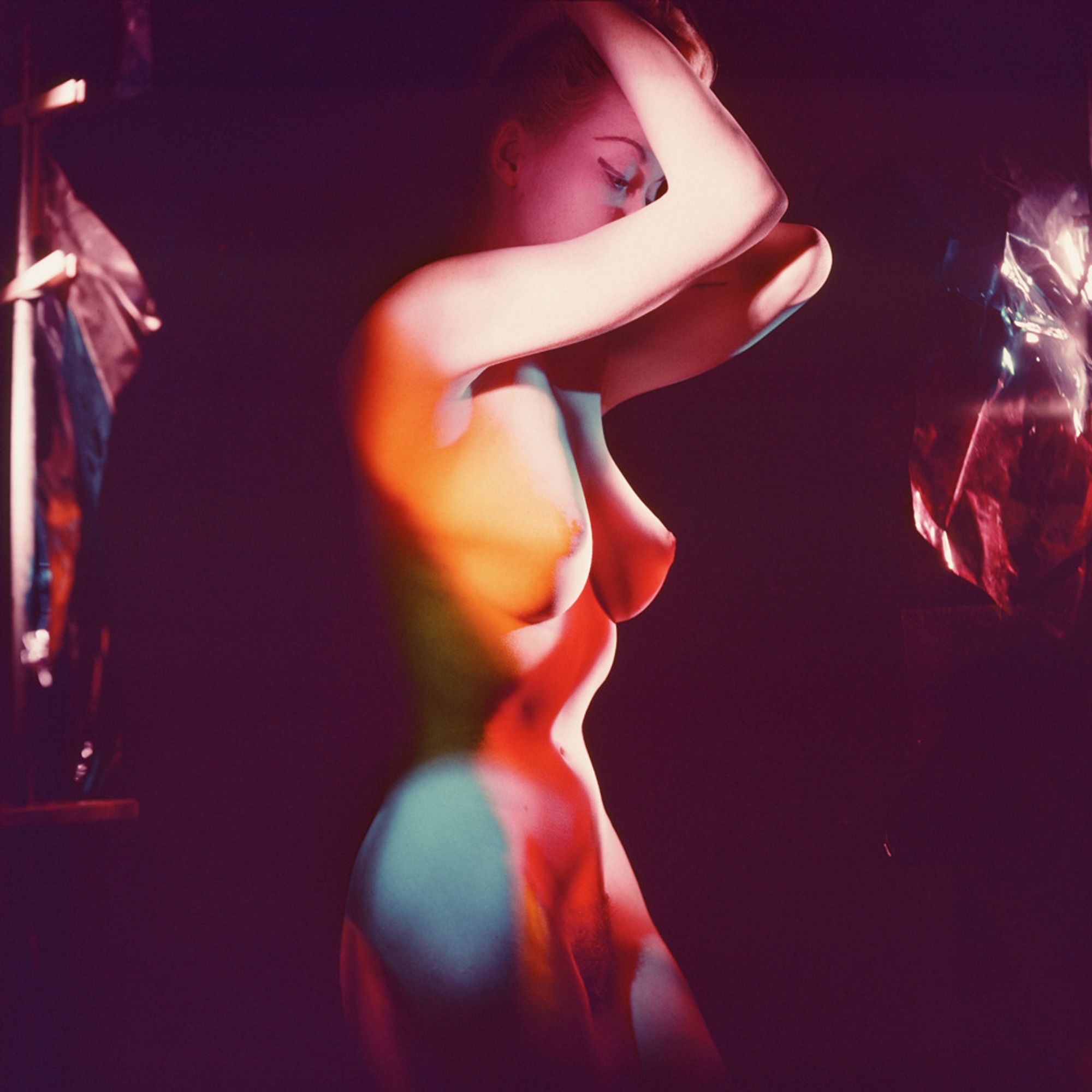 artistic nude photo of Judy O'Day (maybe) by Peter Basch (probably also maybe) posing on a darkened set lit by brightly colored light gels