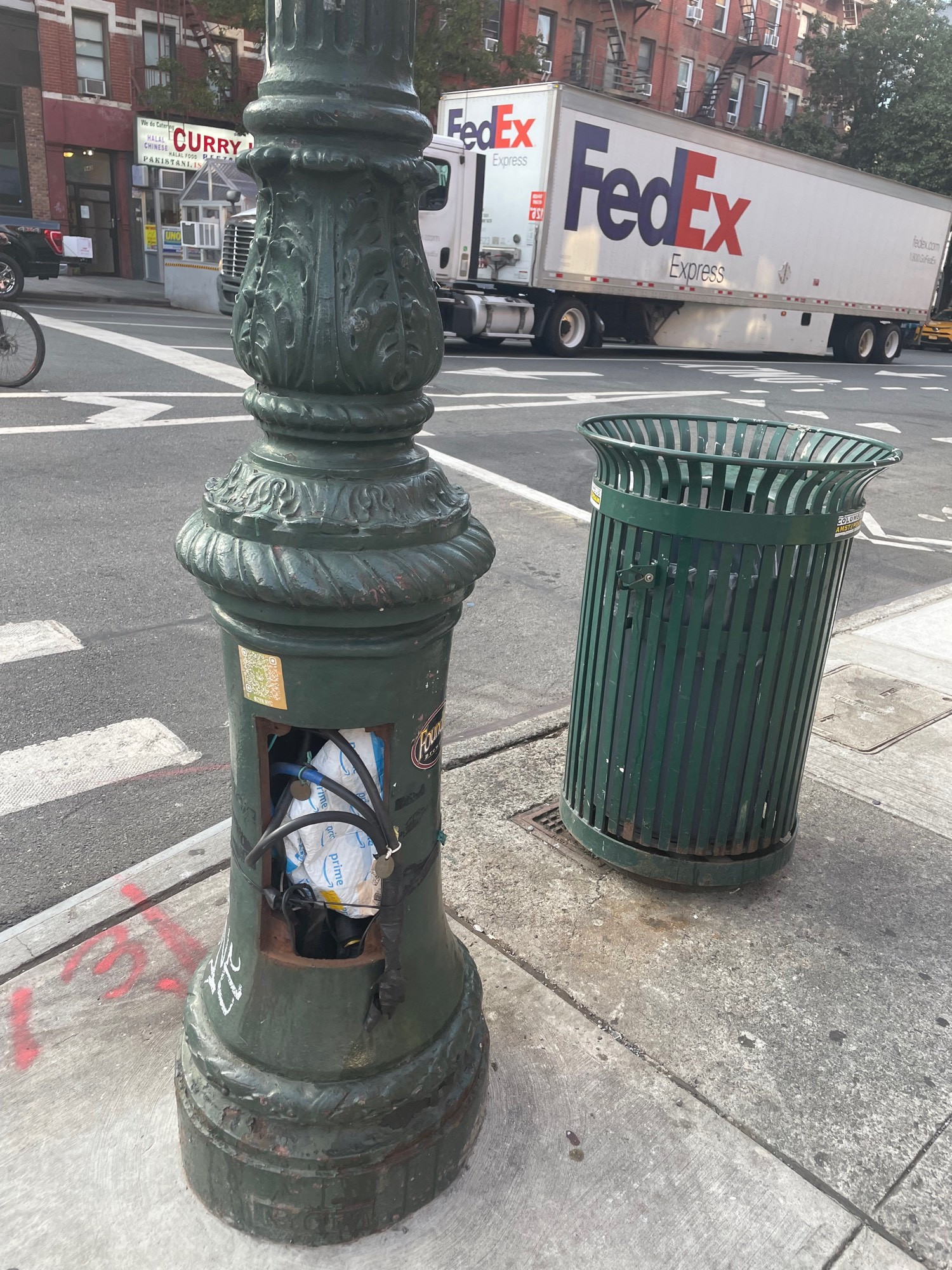 A post for a traffic light, casing open with an Amazon box stuffed inside with the cables
