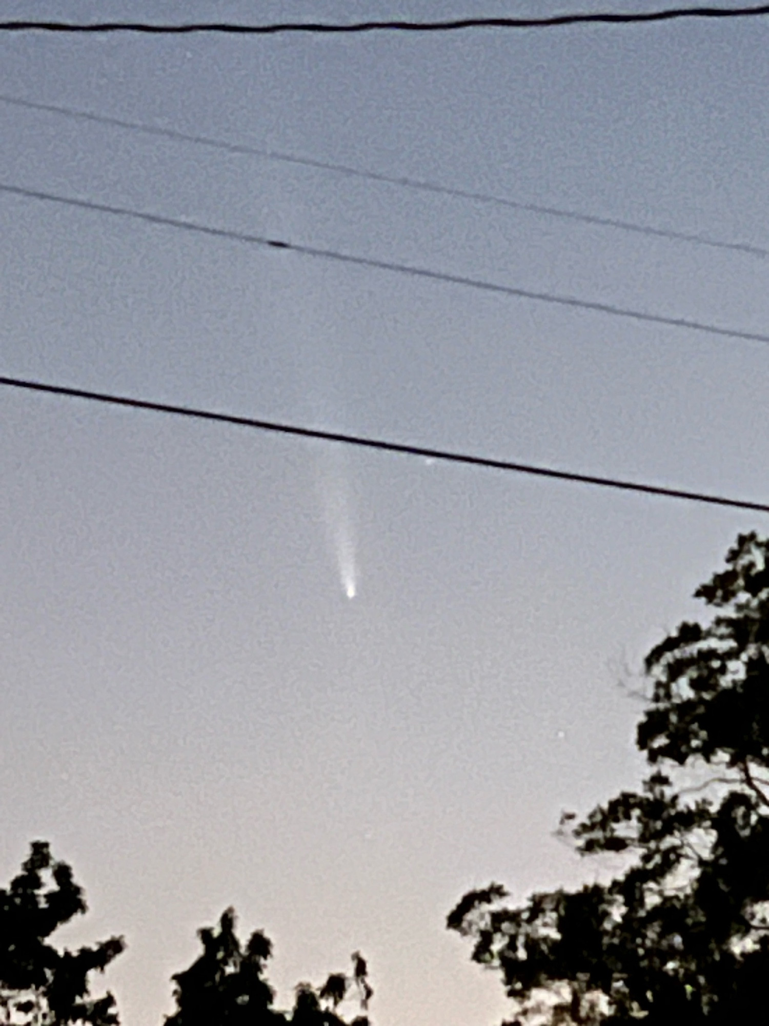 Small white ball with a tail against a light blue and pink sky 