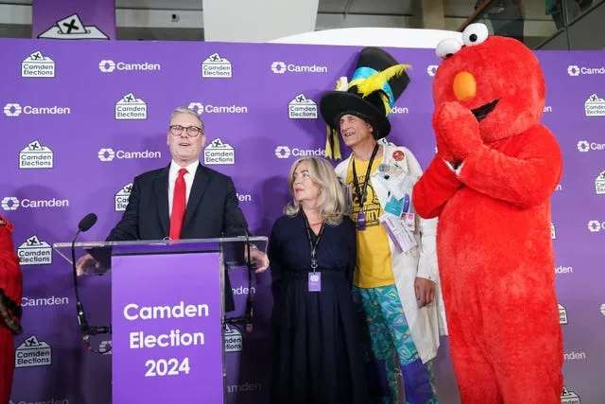 Keir Starmer (left!) gives a victory speech watched by Nick the Incredible Flying Brick and Elmo.