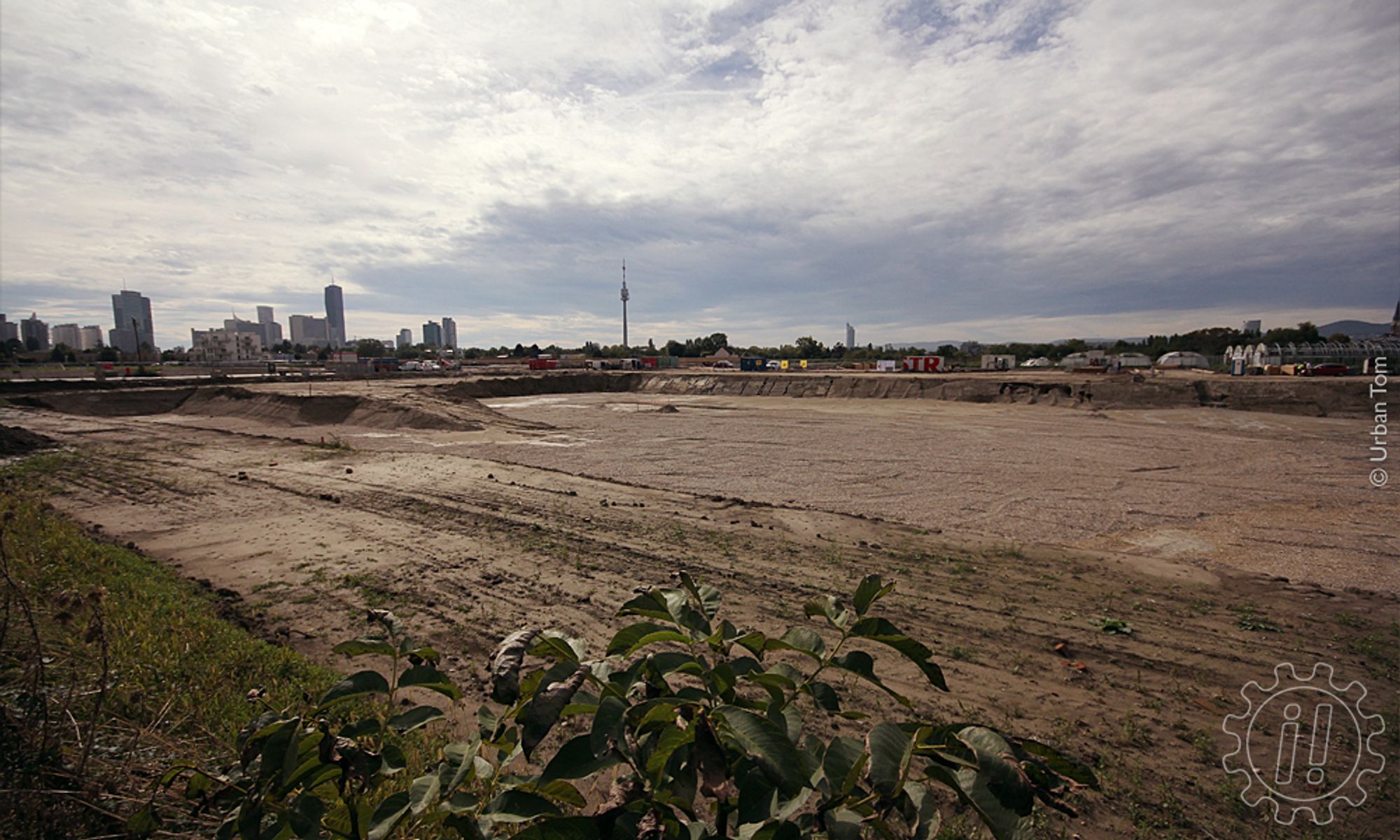 Riesige Baugrube im Donaufeld bei der Dückegasse mit Blick Richtung An der Schanze. Im Hintergrund sind die auf der Donauplatte gebauten Hochhäuser und der Donauturm sichtbar.