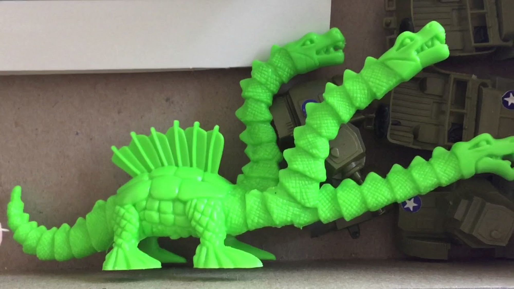 Tricephallon monster from 1970s Godzilla playset. The photo shows a line green plastic monster with three heads and a fin on its back.