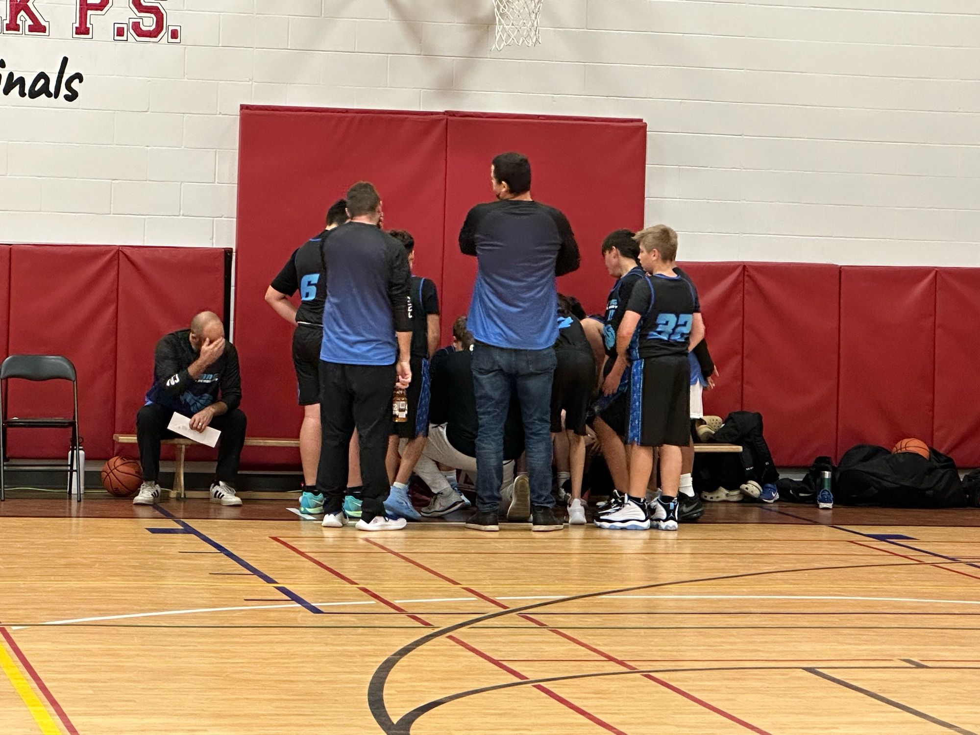 Basketball team huddling at the bench. Squeezed out the win. Good first game. 