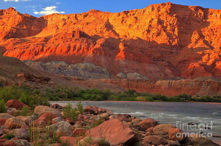 Sunset lights up the towering red rock cliffs along the Colorado River at Lee’s Ferry at the edge of the Grand Canyon in Arizona.  Photo by Adam Jewell.  Buy prints, puzzles, fleece blankets and more at https://adamjewell.com/featured/reflections-over-the-colorado-adam-jewell.html