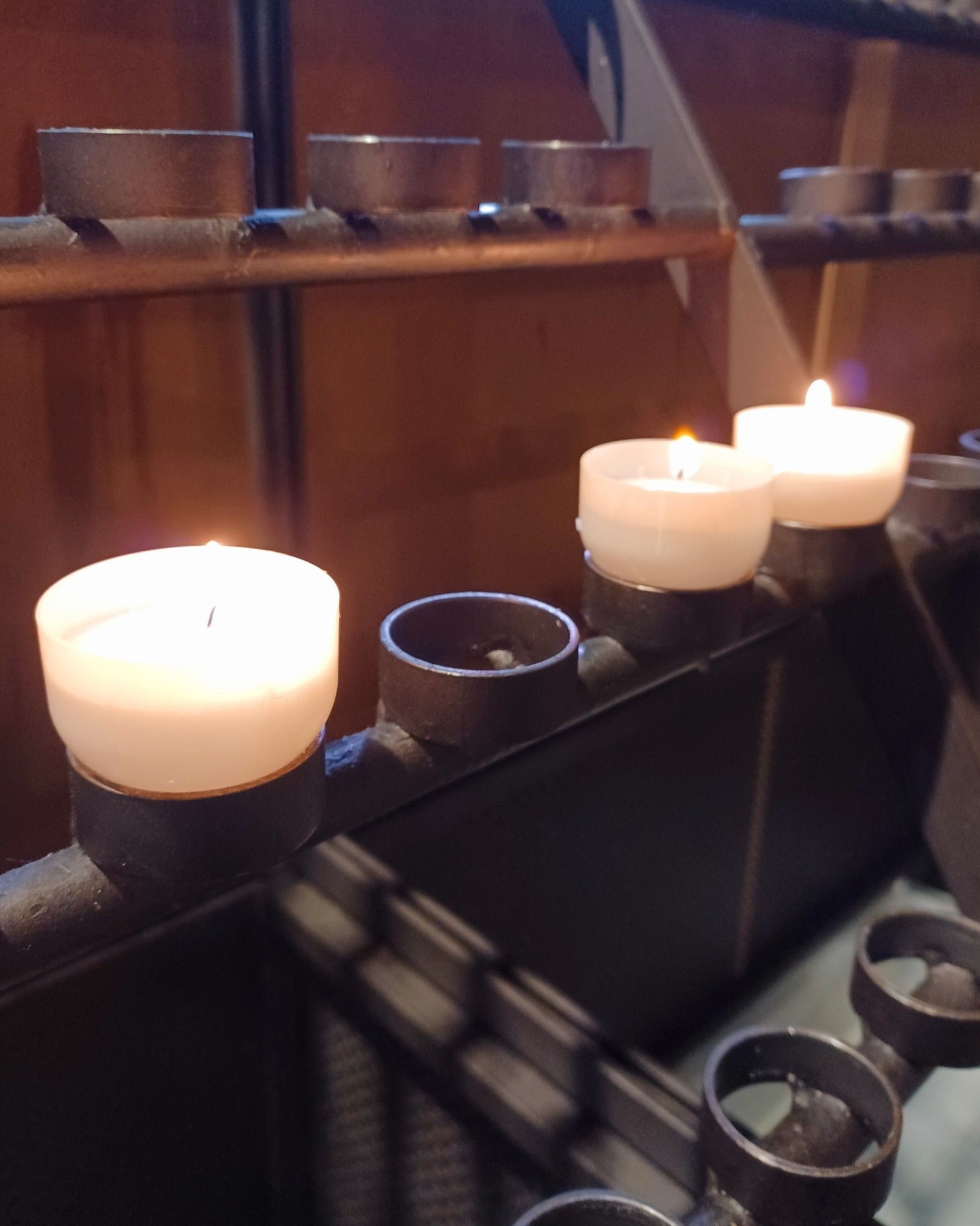 A photograph of three lit votive candles in a church.