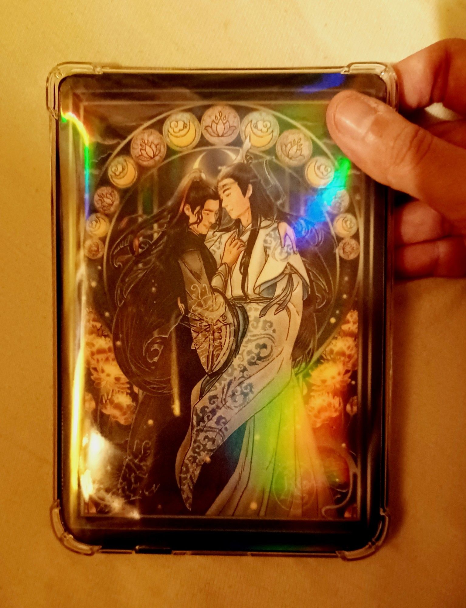 OP holding her e-reader. It has a clear silicone backing on, under which OP has slipped a printout of a Wangxian fanart in Art Nouveau style, that OP has drawn herself.