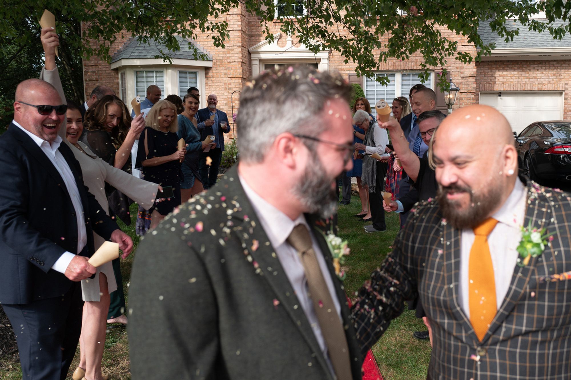 The groomsmen exit their wedding while the party looks on, smiles all around - Leica Q