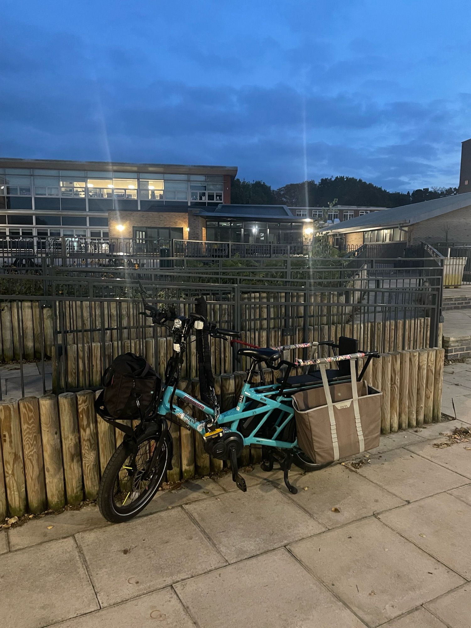 A blue cargo bike locked to railings.