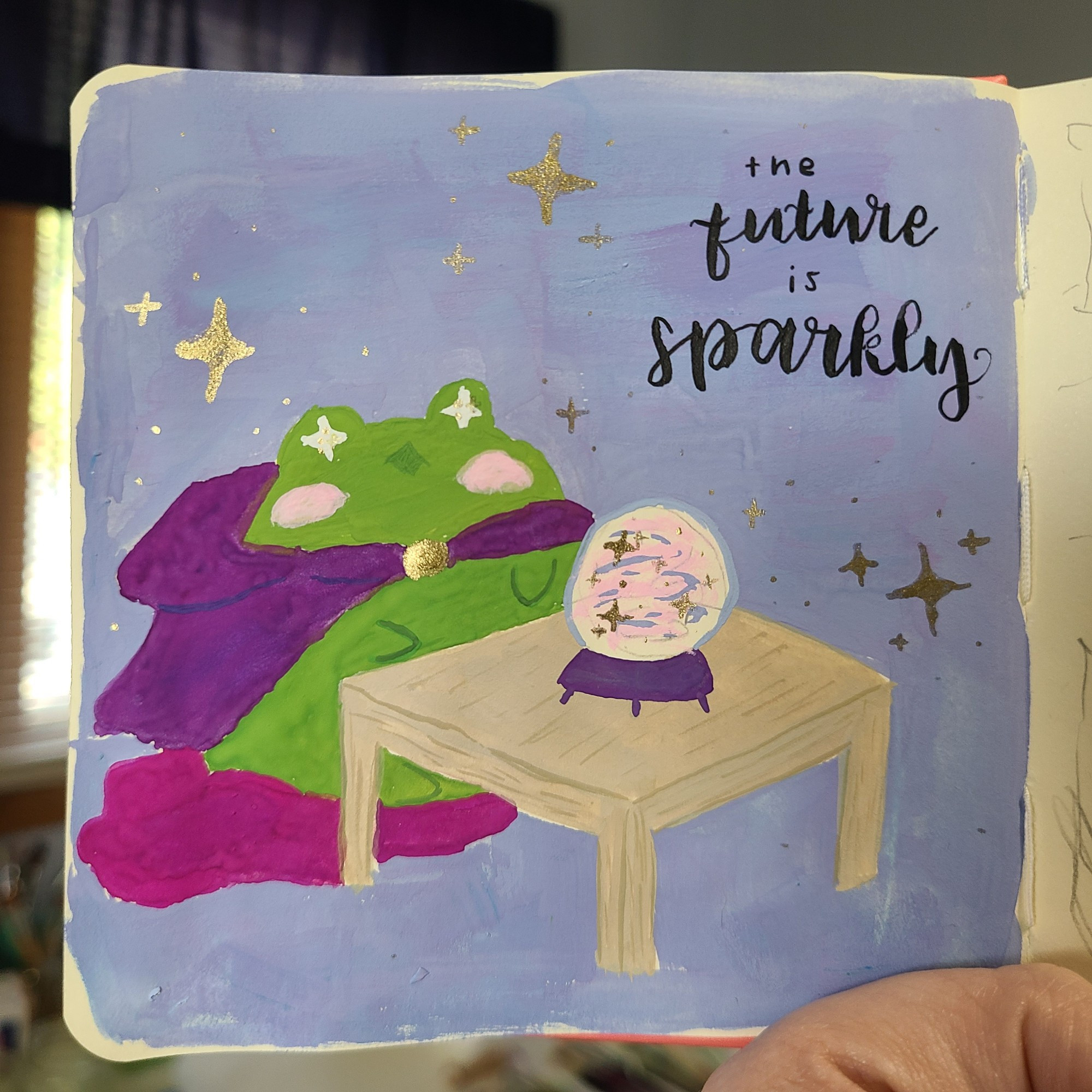 A very round green frog in a purple hooded cloak sits upon a pink cushion front of a swirly, sparkly crystal ball. His eyes light up with a sparkler as he tells you "the future is sparkly" gold stars and sparkles shine around him 